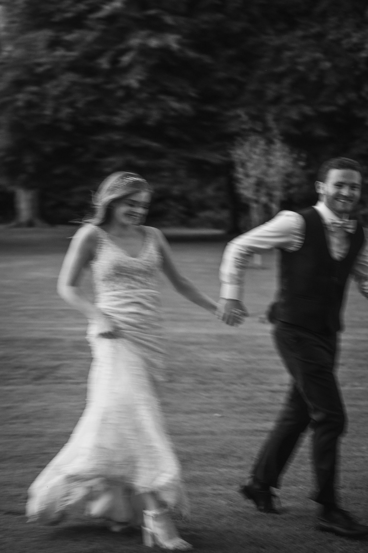 laughing bride and groom joyfully running hand in hand across a lawn at Rathsallagh House wedding in Wicklow.