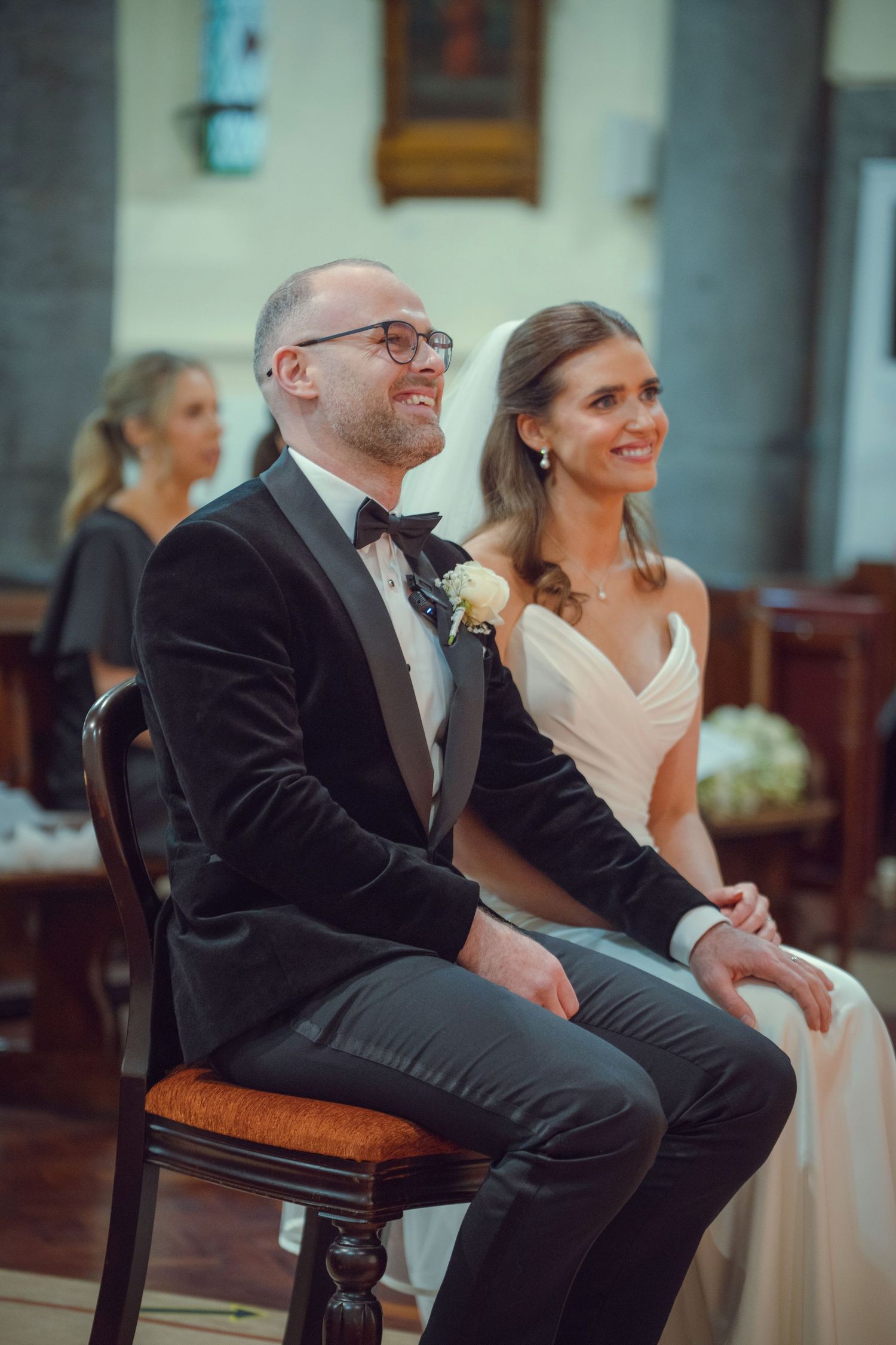 Smiling bride and groom seated together during wedding ceremony inside a church at Mount Juliet wedding Kilkenny.
