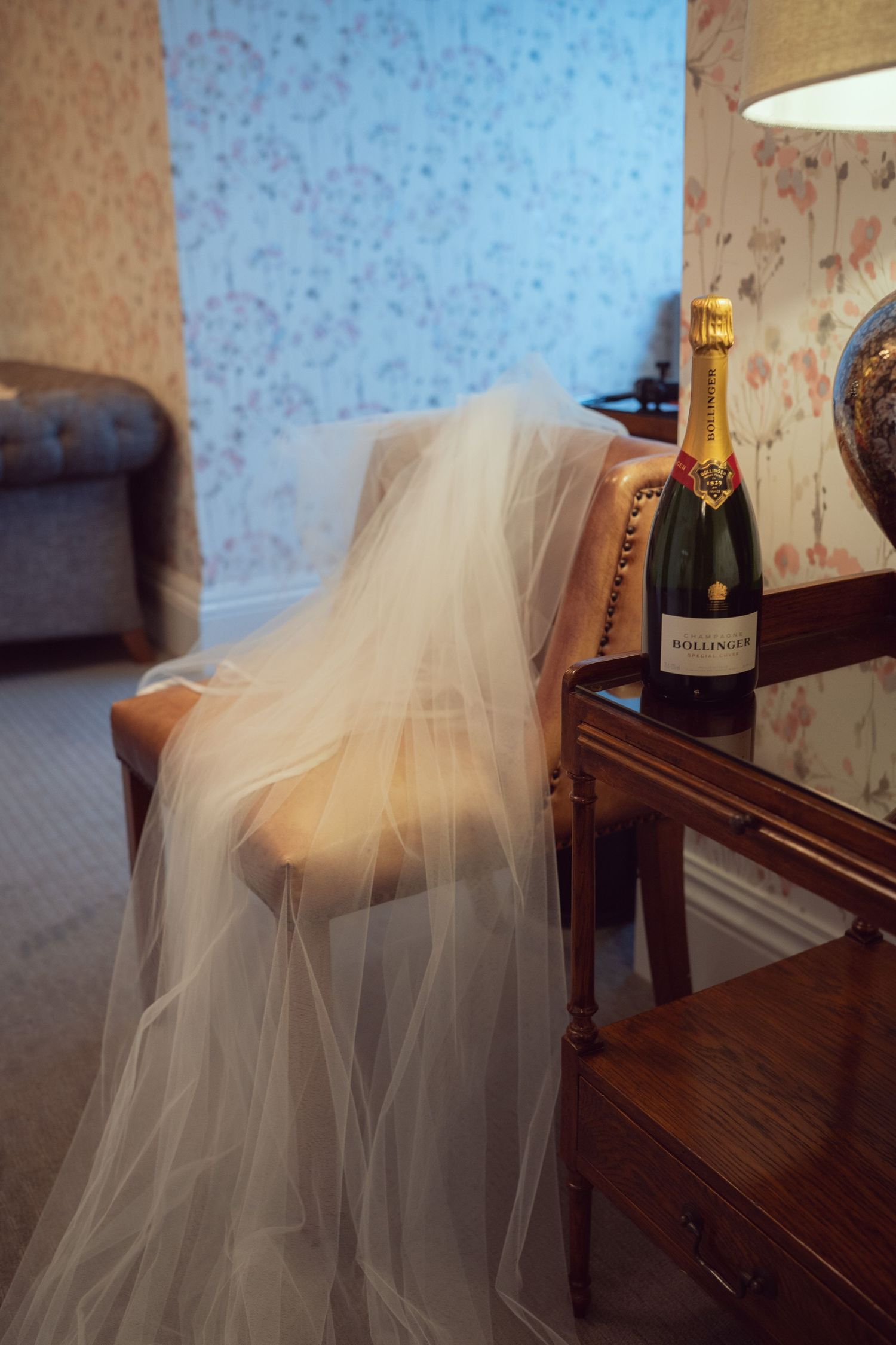 Bridal veil draped over chair beside Bollinger champagne bottle in elegant hotel room at Mount Juliet wedding in Kilkenny.
