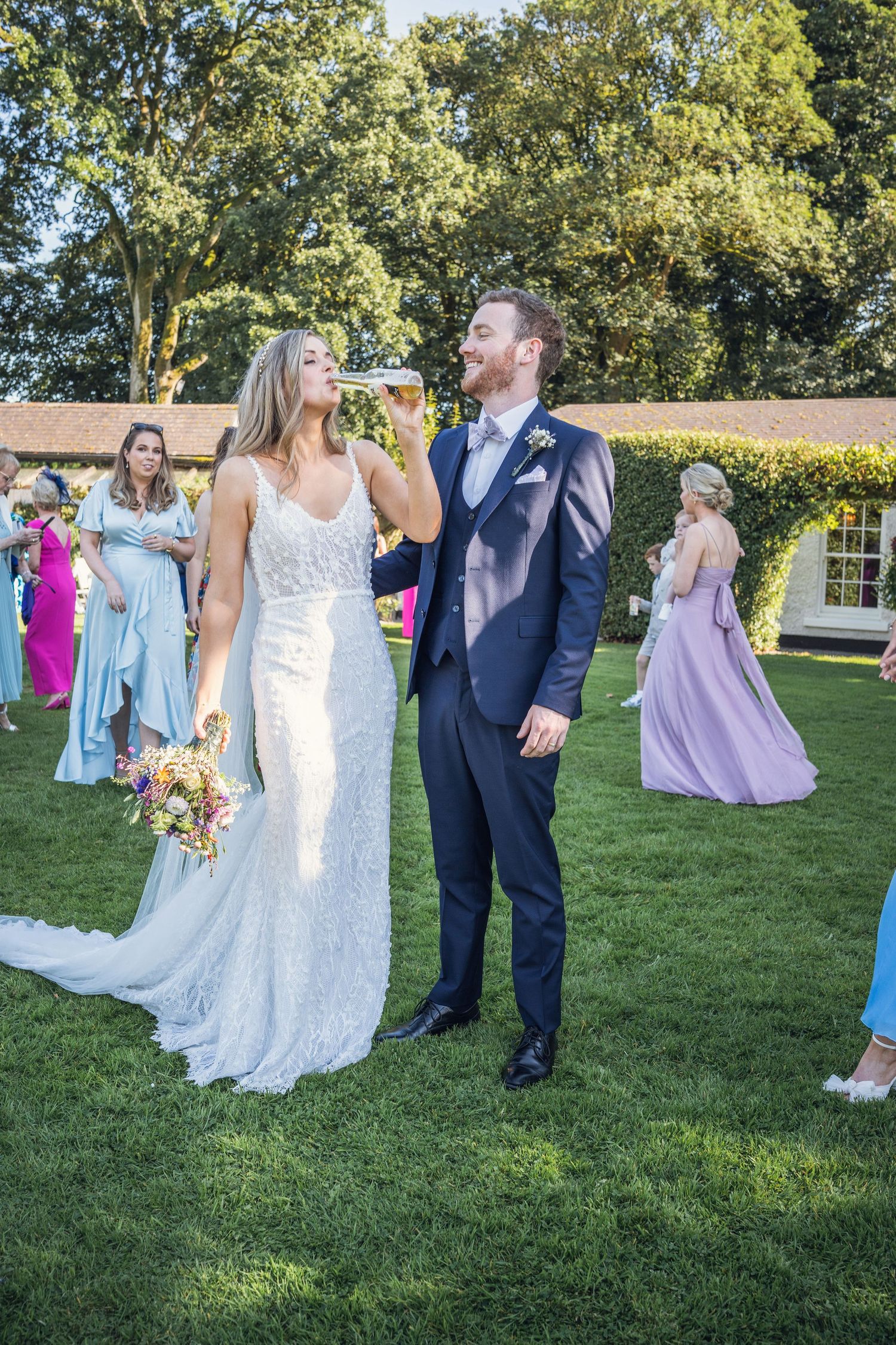Bride and groom enjoying outdoor wedding reception on lush green lawn.