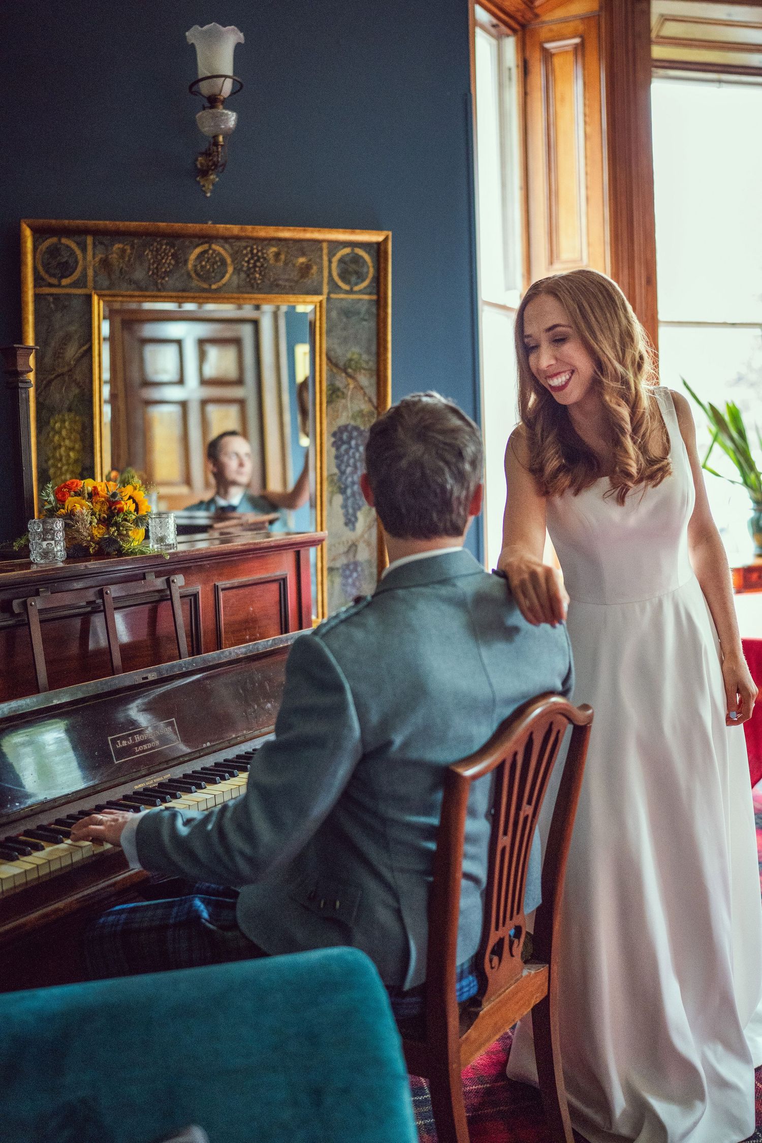Laughing bride watches groom play piano in elegant room at Tinakilly House wedding in Wicklow,