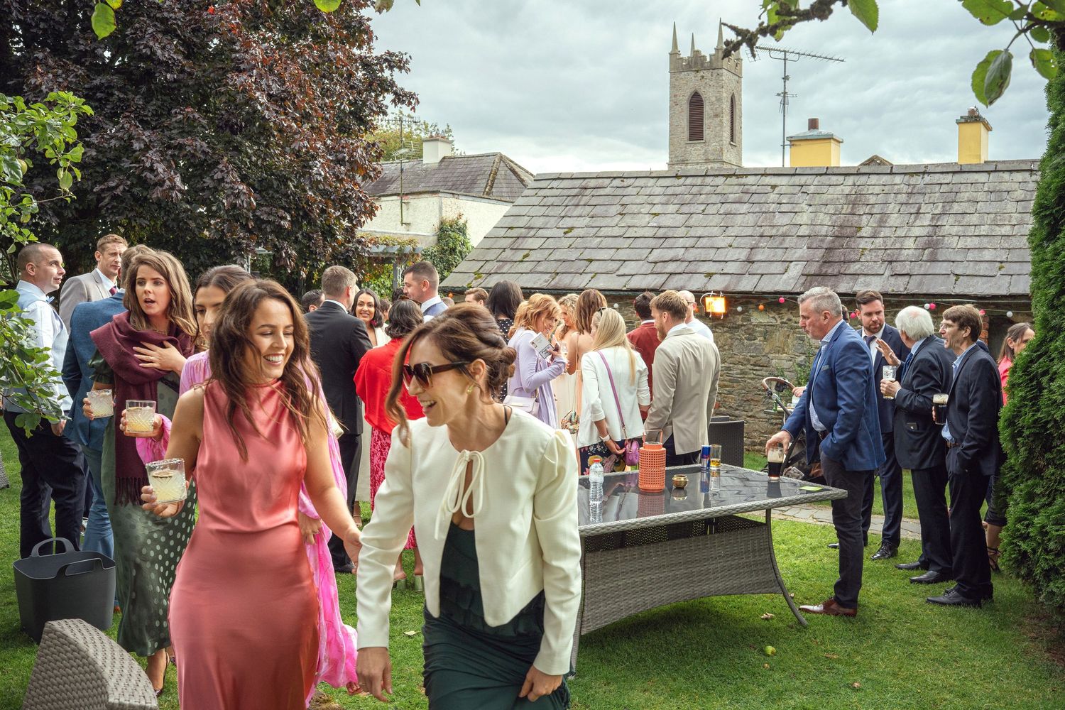 Elegantly dressed wedding guests mingle outdoors at outdoor garden wedding reception in Co Meath.