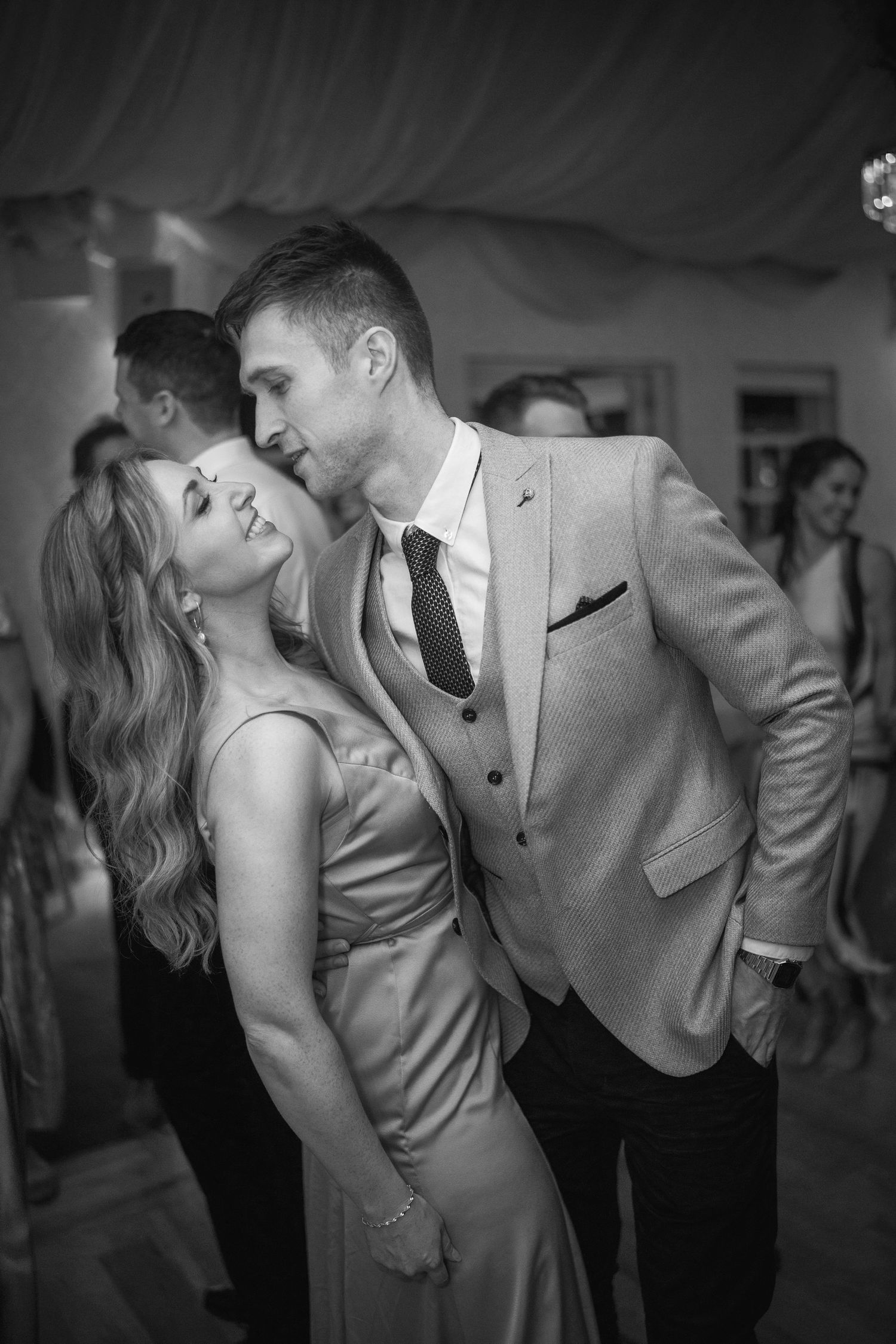 Black and white photo of an elegant couple dancing closely together at a wedding reception.