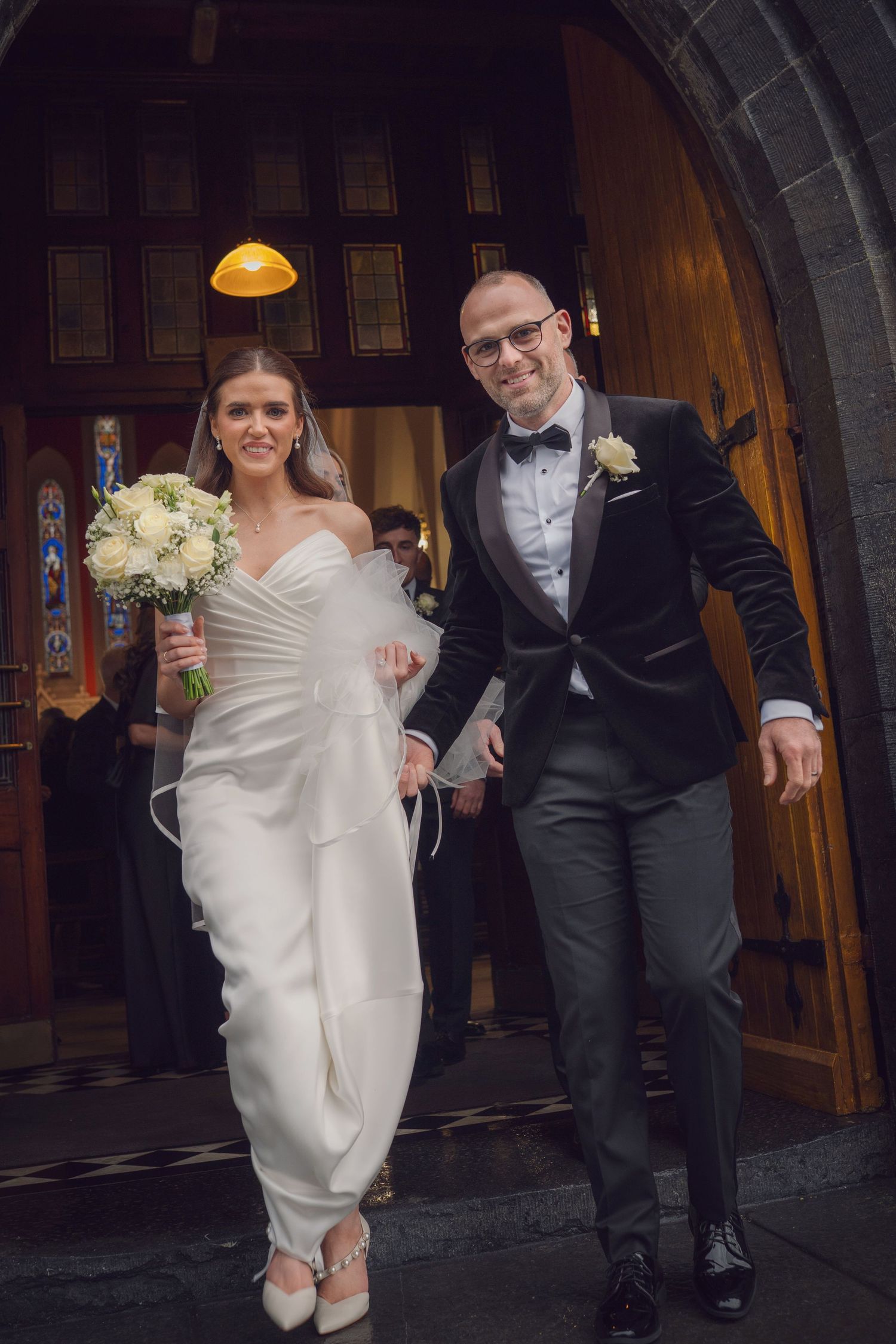Newlyweds smiling and holding hands while exiting church at Mount Juliet wedding Kilkenny.