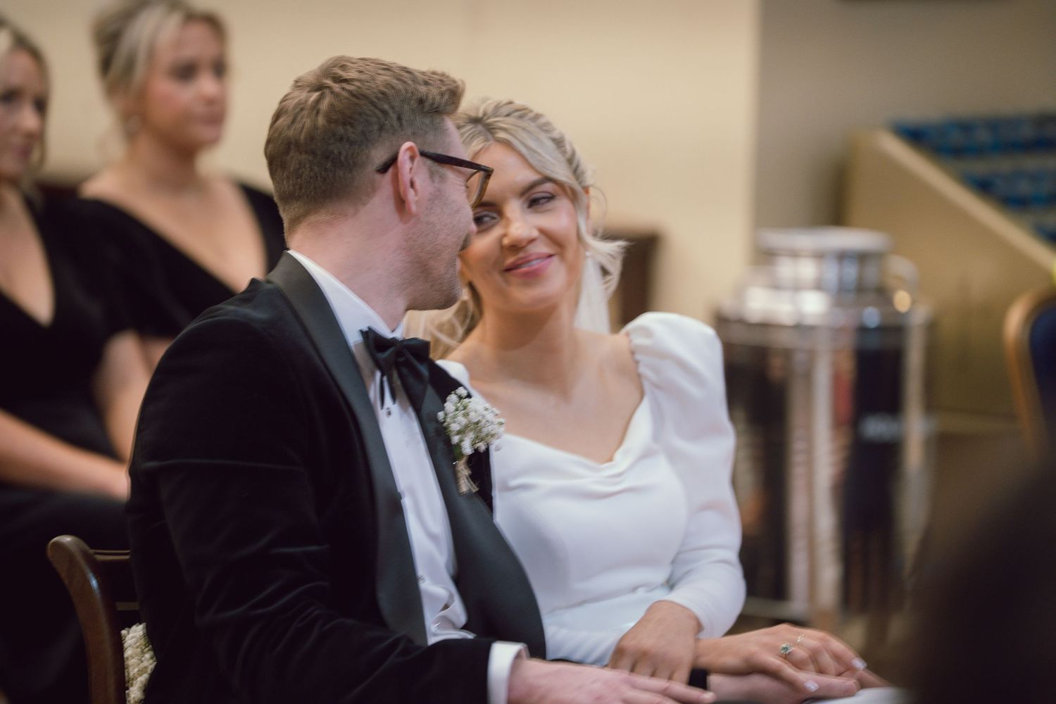 Bride and groom share an intimate glance while seated together during their wedding ceremony.