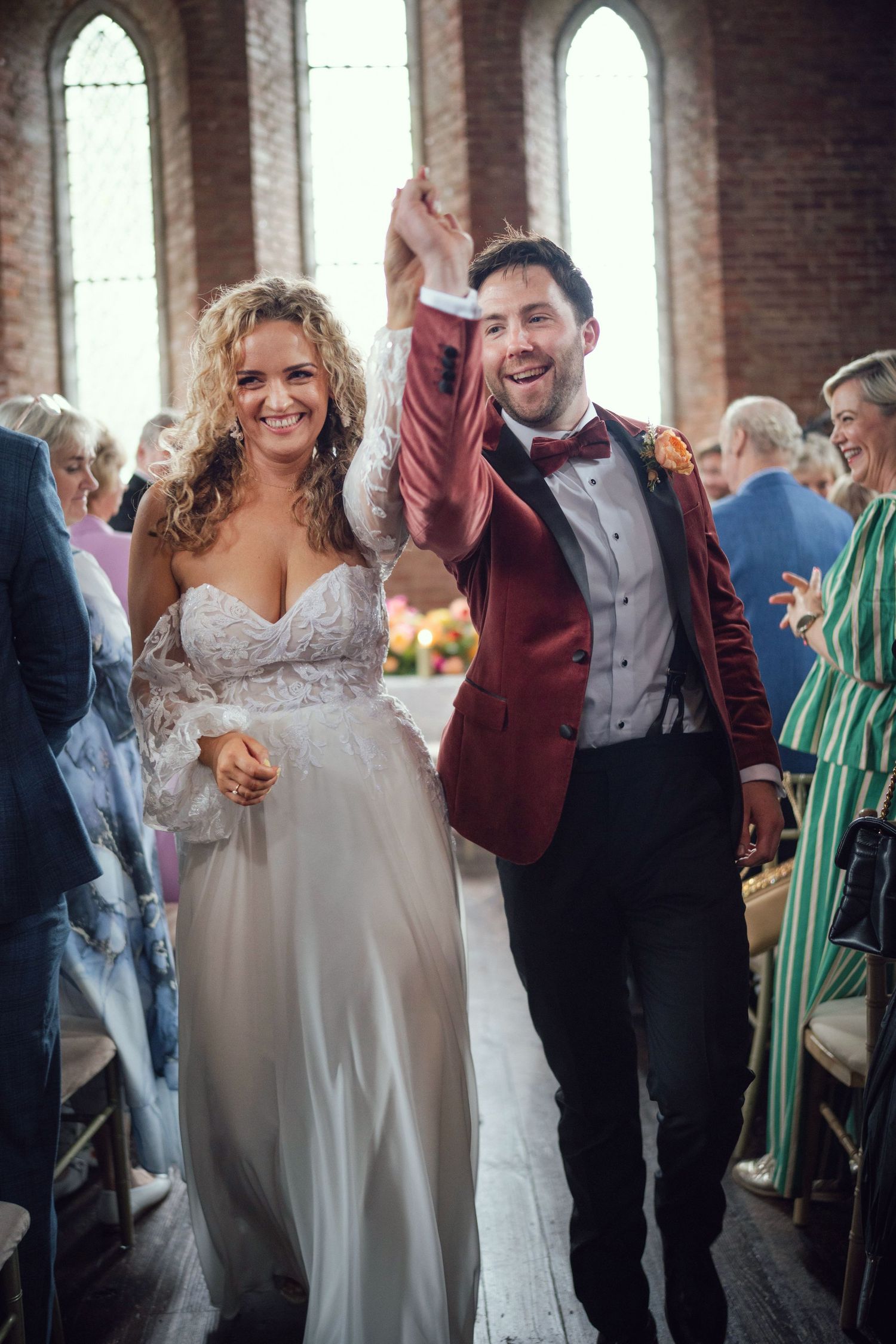 Joyful newlyweds walk down church aisle celebrating after wedding ceremony at red chapel Kells in Co Meath.