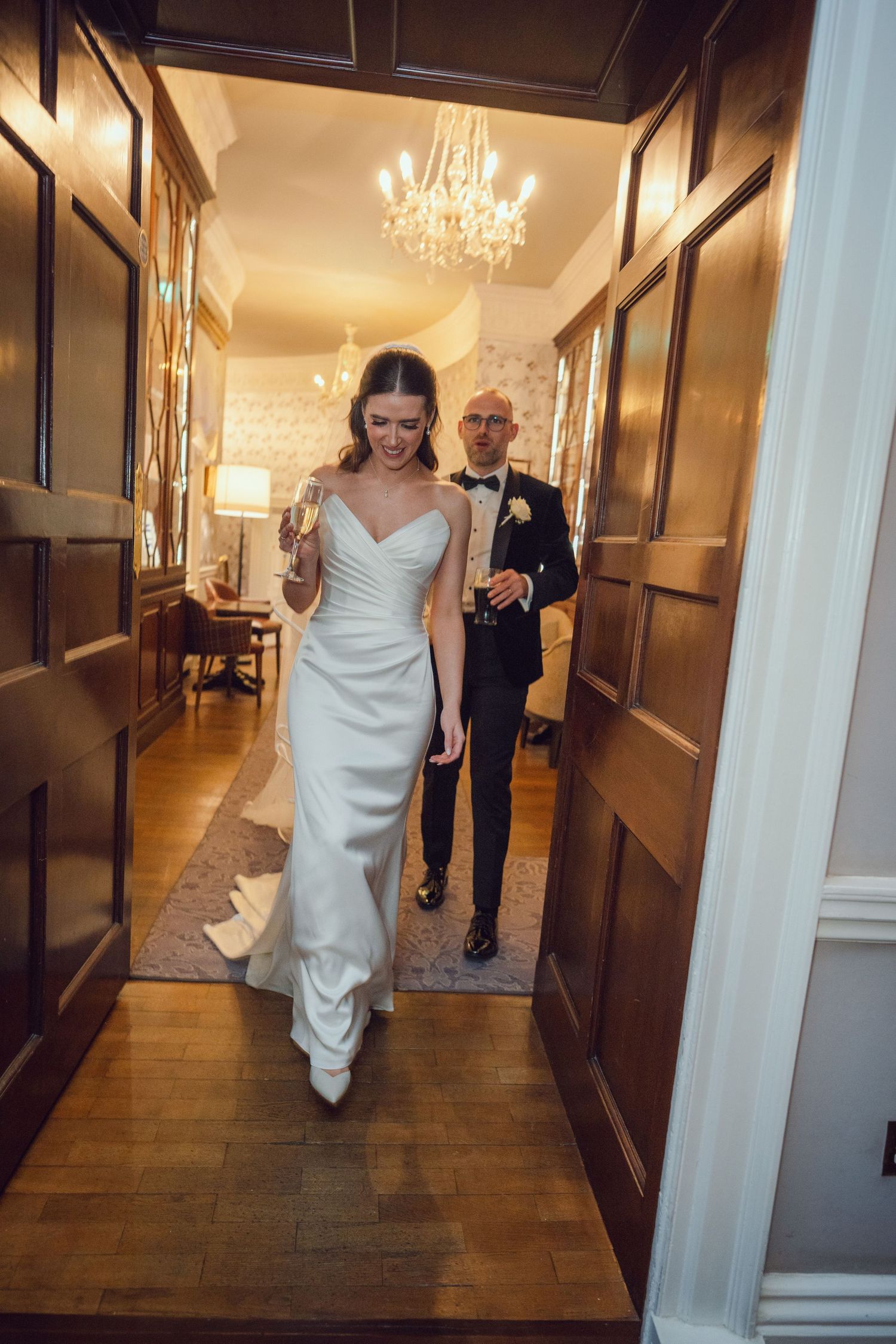 Bride leads groom through a luxurious wood-paneled hallway at the Manor House Mount Juliet wedding Kilkenny.
