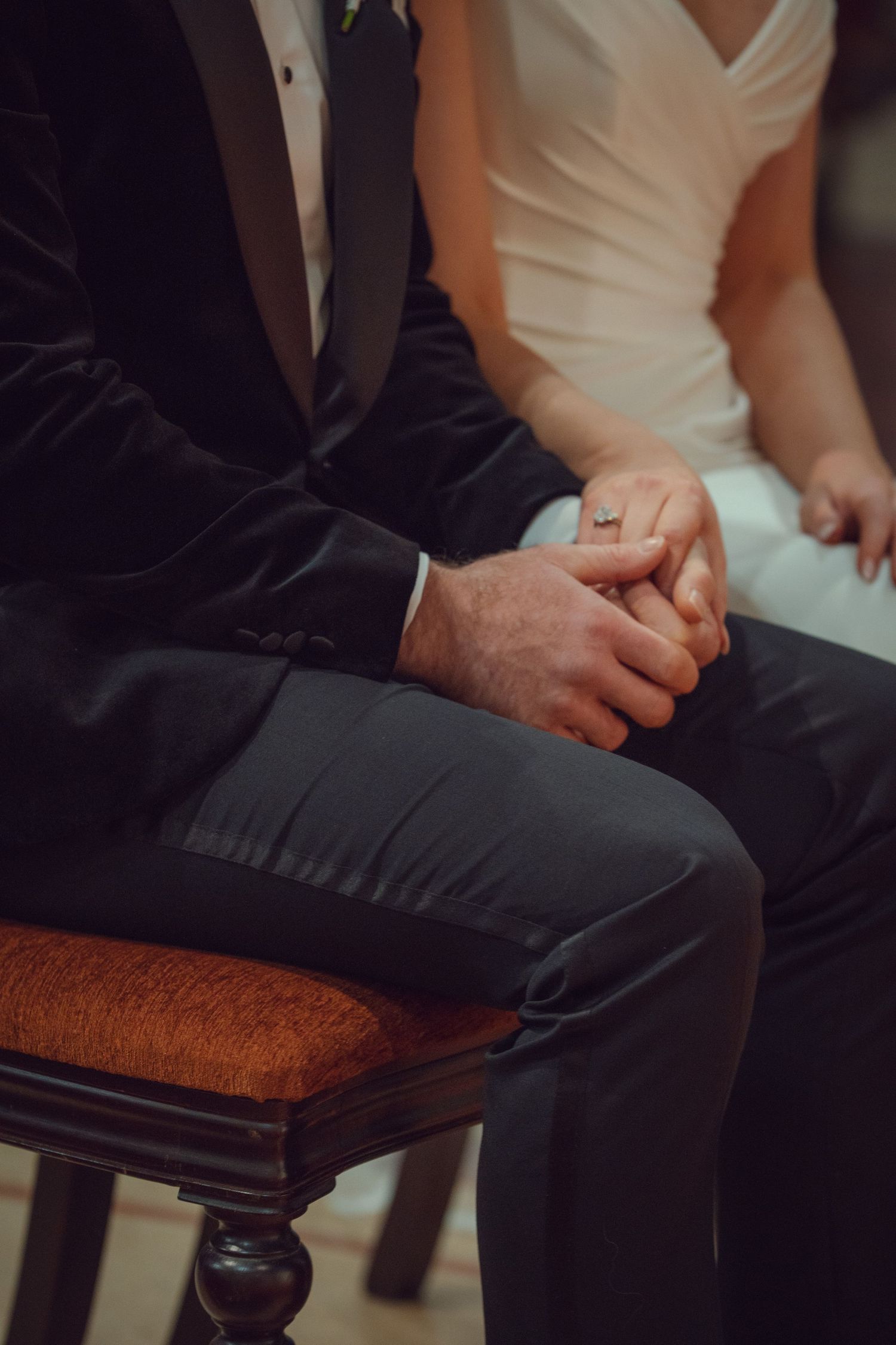 Bride and groom holding hands while seated during wedding ceremony at Mount Juliet wedding in Kilkenny.