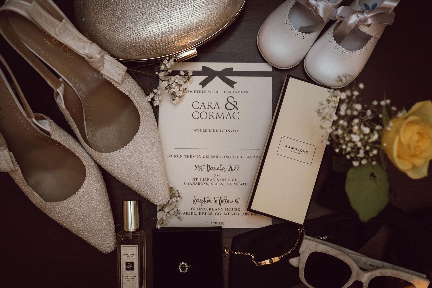 Flat lay of wedding stationery, shoes, perfume, and accessories for Cara and Cormac's wedding day.