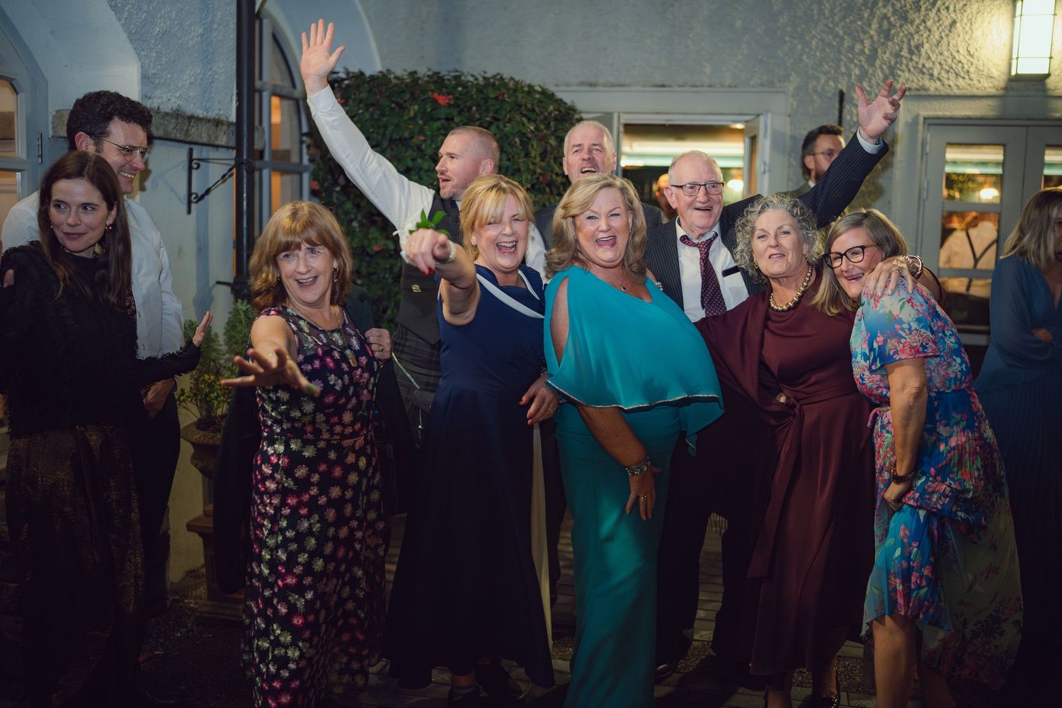 Joyful wedding guests celebrating outdoors at night, raising hands and smiling for a group photo at Mount Juliet wedding in Kilkenny.
