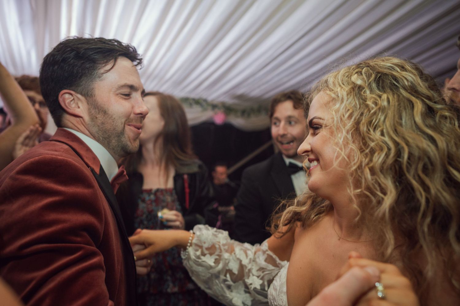 Bride and groom share a joyful dance together at their wedding reception inside a decorated marquee at outdoor garden wedding reception in C