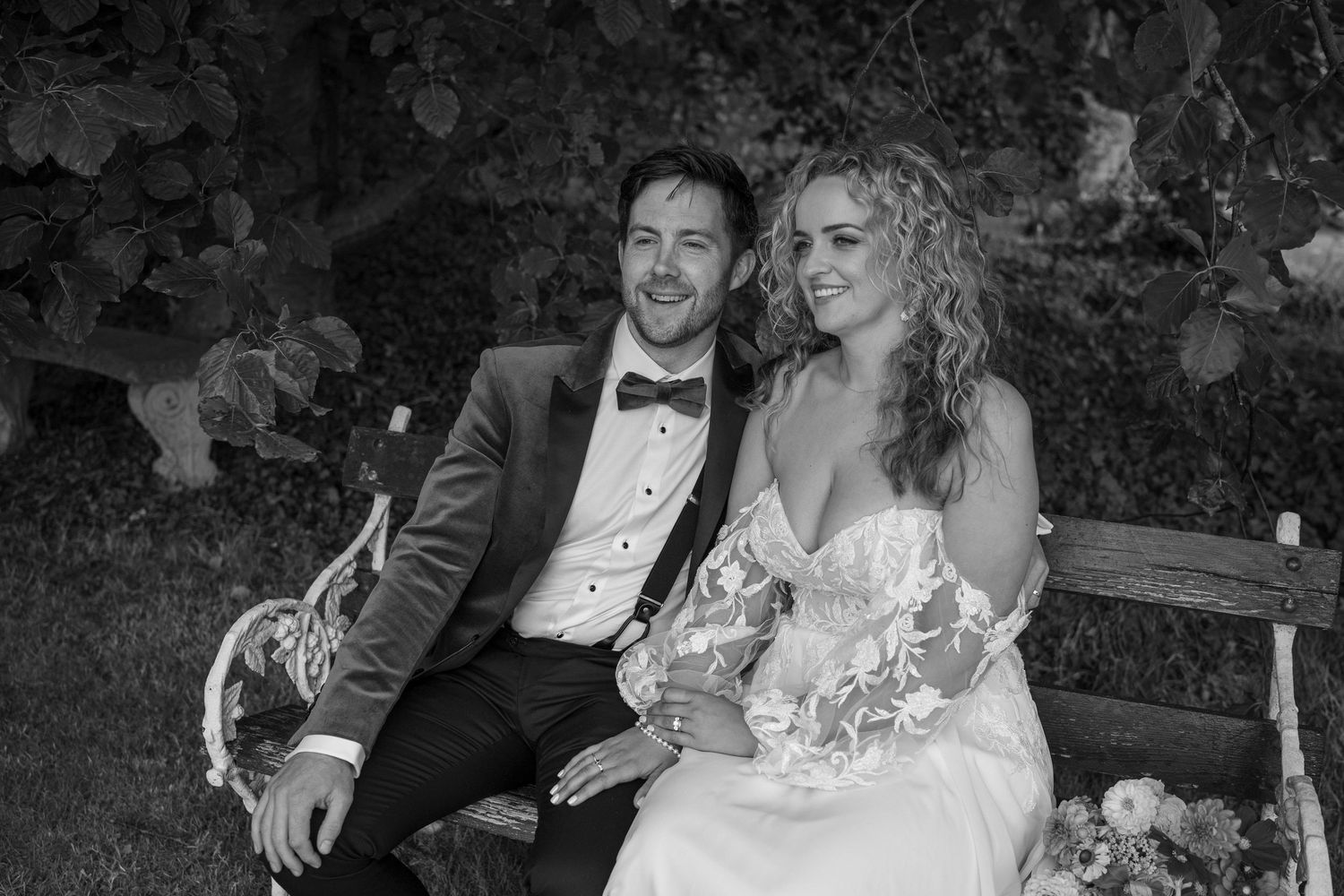 Portrait of smiling bride and groom sitting together on a bench outdoor garden wedding reception in Co Meath.