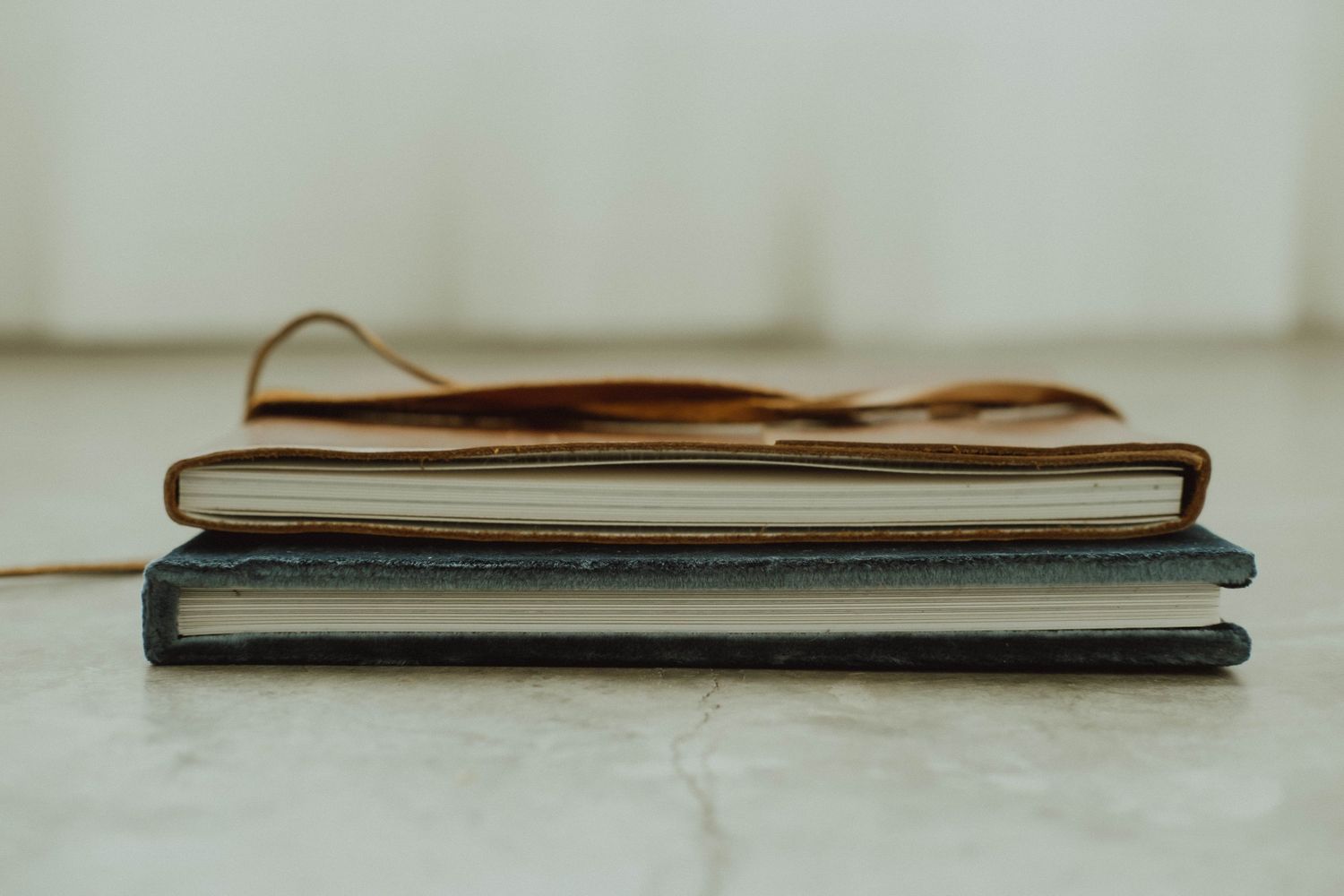 Old worn leather books with weathered pages lay in a row on a white surface, showing their aged spines and textures.
