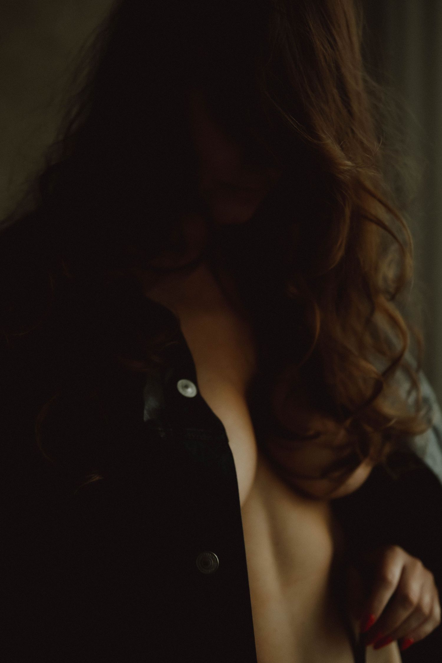 Dark and moody portrait series showing close-up details of curly brown hair and skin in dramatic shadows.