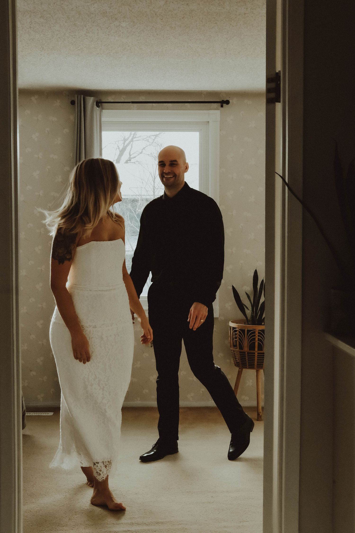 Dancing couple in wedding attire captured in a minimalist studio setting through multiple glass panel reflections.
