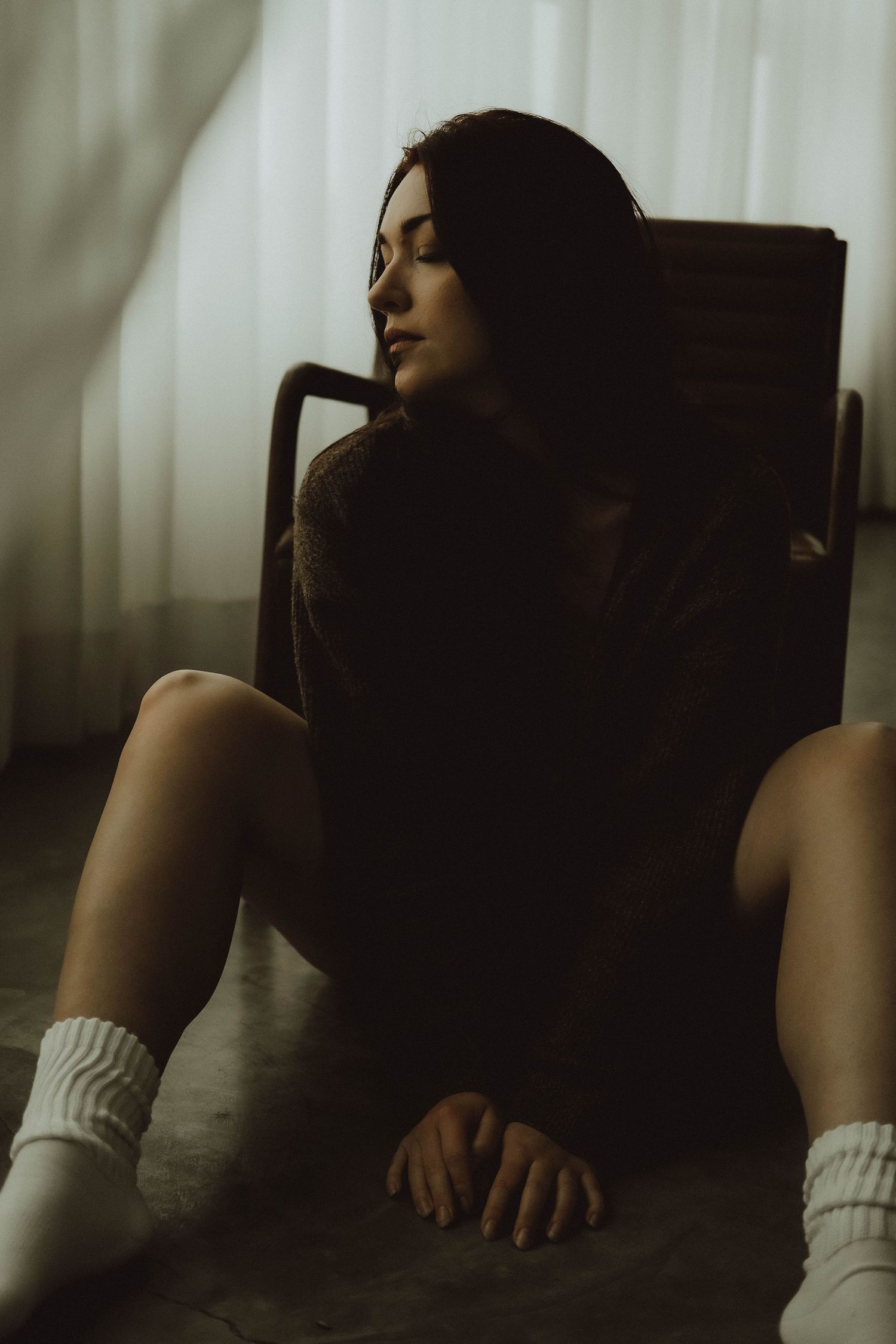 A person in a white top rests against a dark chair in moody, atmospheric lighting with multiple poses shown.