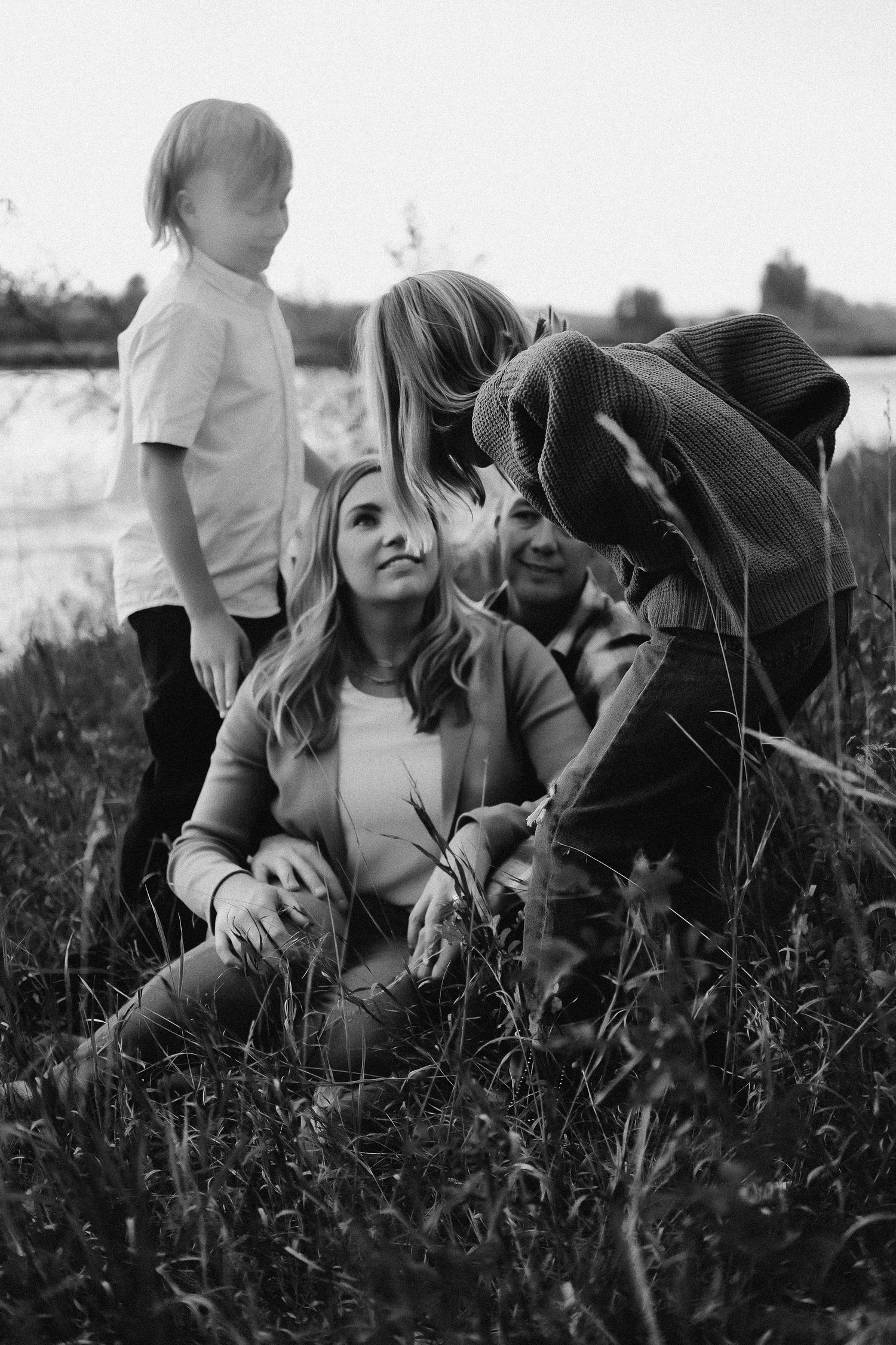 A black and white photo sequence showing a tender moment between two people lying in a grassy field.
