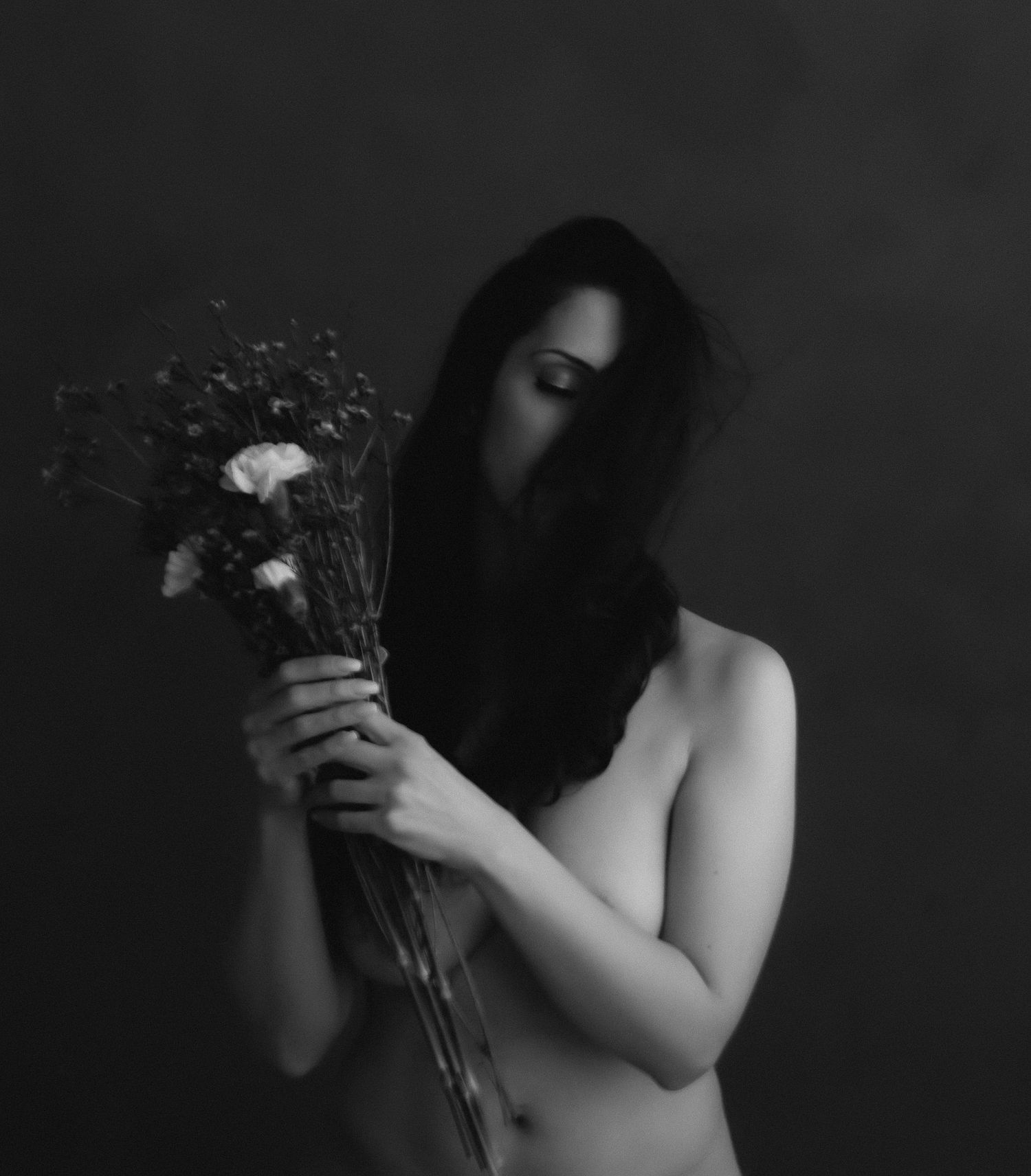 A dramatic black and white photo series shows someone holding flowers against a dark background.