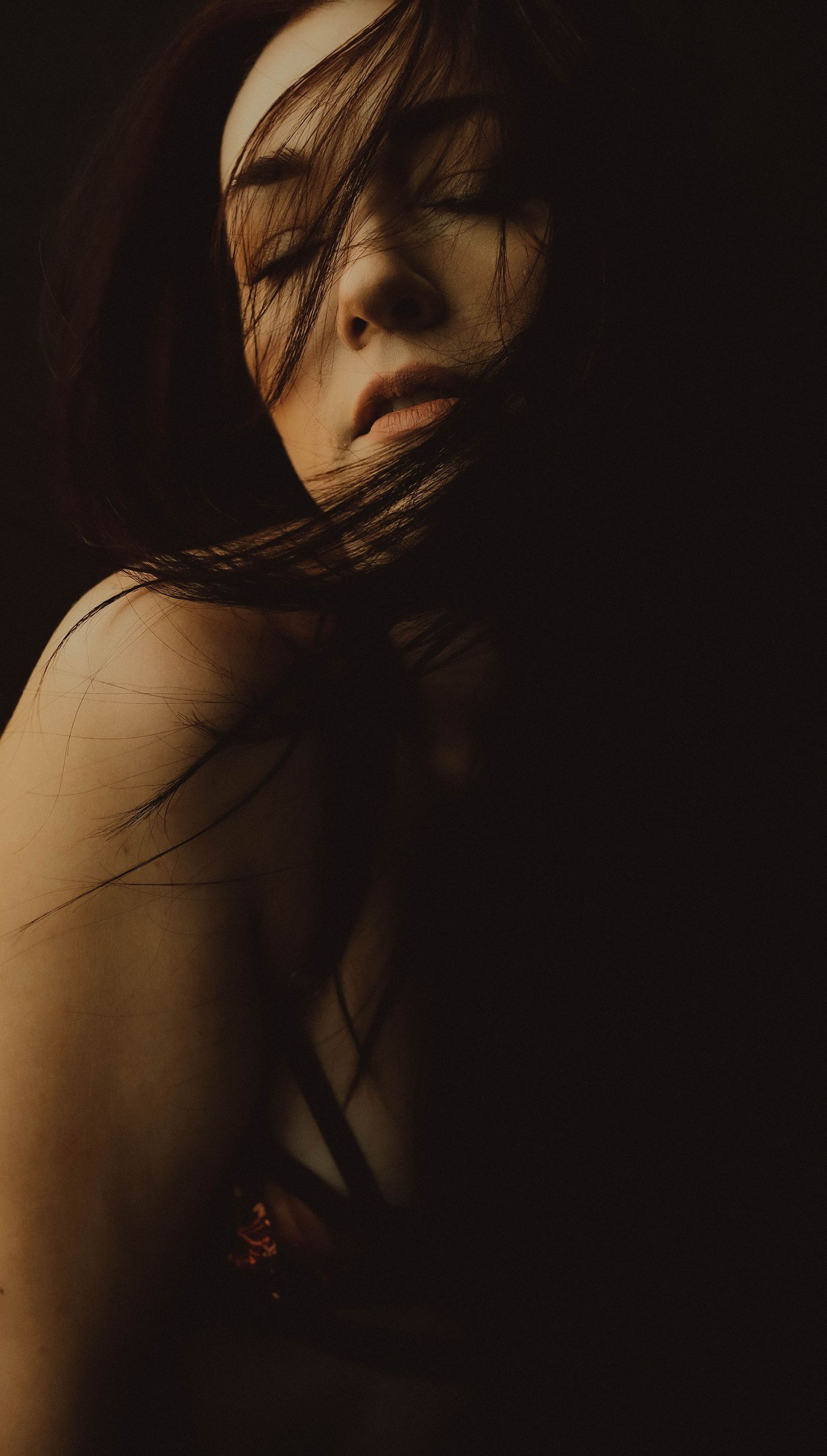 Artistic dark and moody portrait series showing dramatic shadows and movement against a black background.