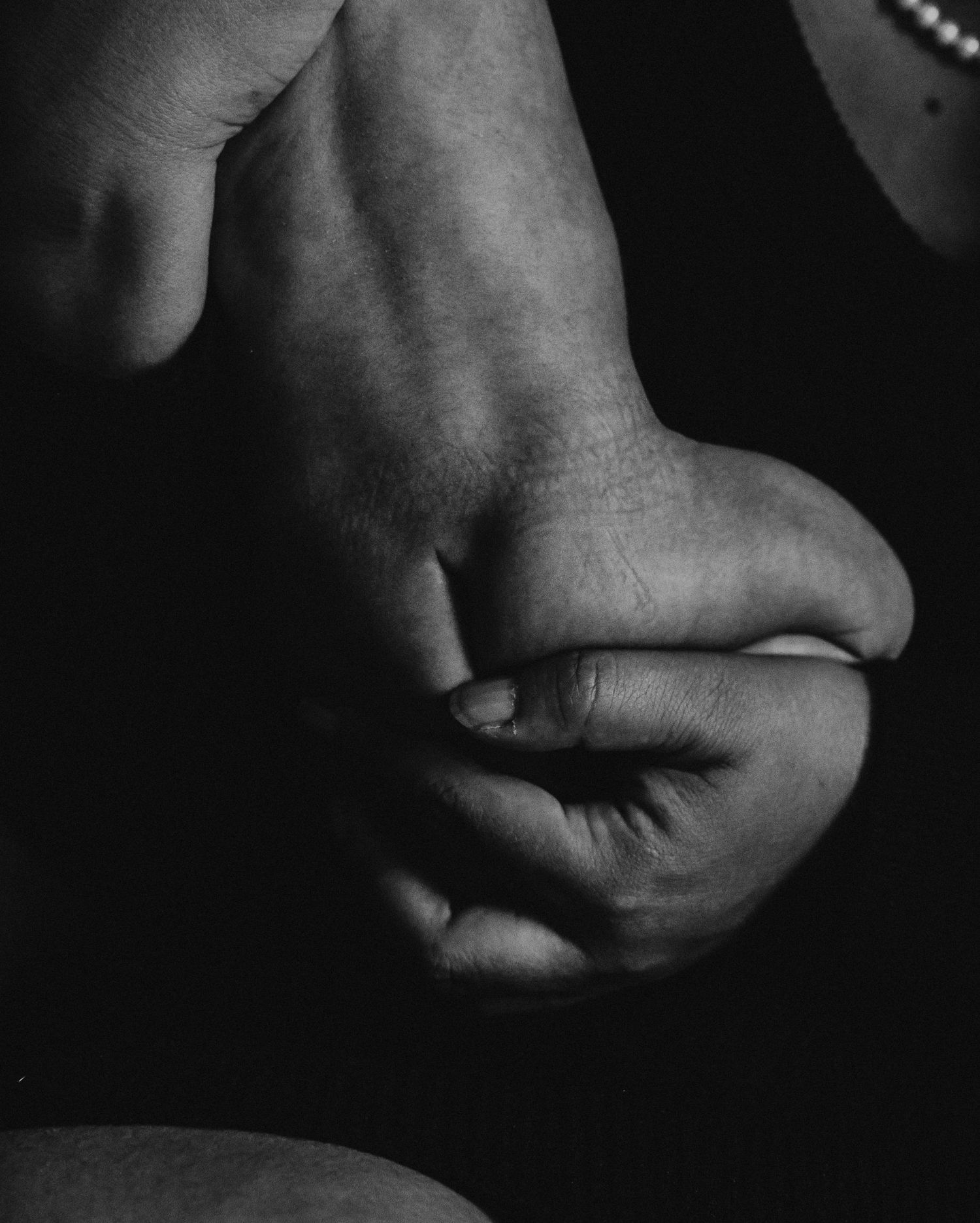 Black and white artistic photograph showing a series of hands in shadow against a dark background.