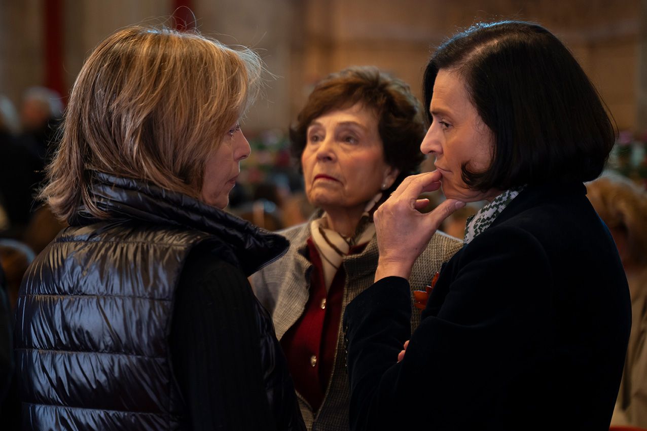 Three women engaged in conversation at an indoor event in a dimly lit venue.