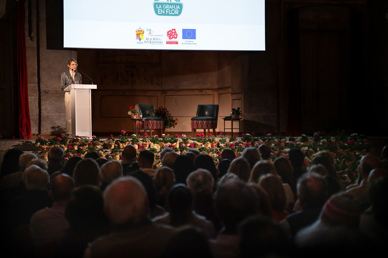 Speaker at podium addresses packed audience in grand hall with EU and event logos on screen.