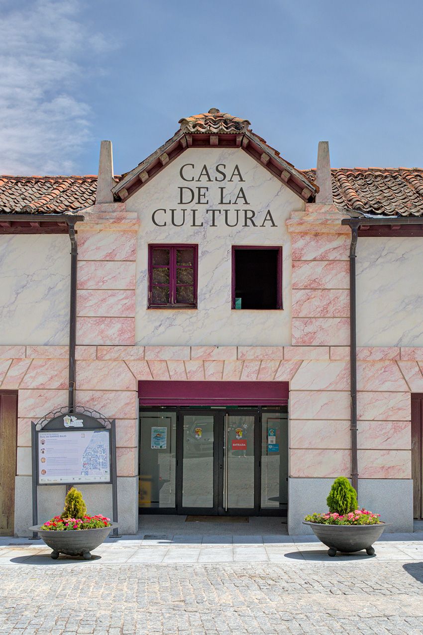 Exterior facade of Casa de la Cultura cultural center with pink marble walls and flower pots at entrance.