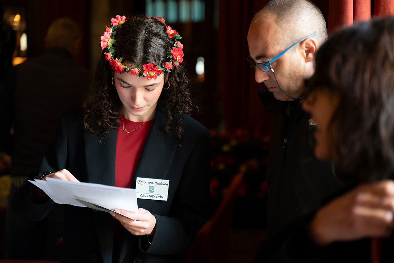 Young woman with floral crown reviewing documents with attendees at a spring festival.