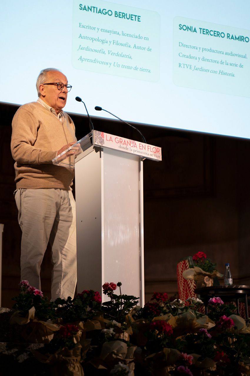 Speaker at a podium during La Granja en Flor event, with a presentation screen visible behind him.
