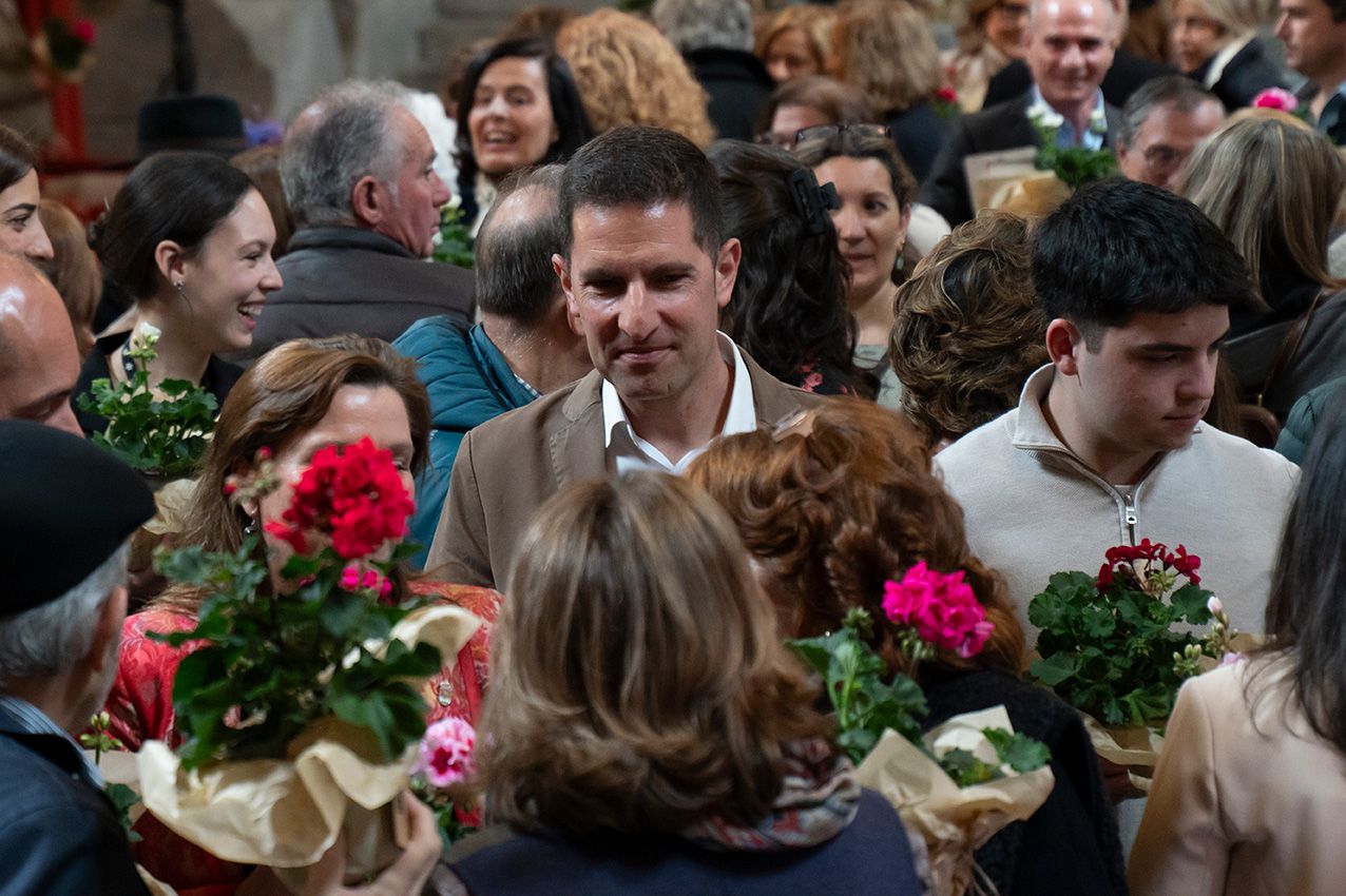 Man surrounded by crowd holding colorful flower bouquets at a spring floral festival event.