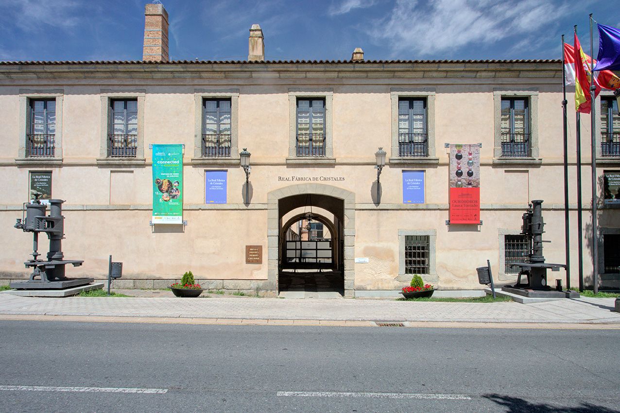 Historic stone building museum facade with colorful banners, flags, and sculptures under a clear blue sky.