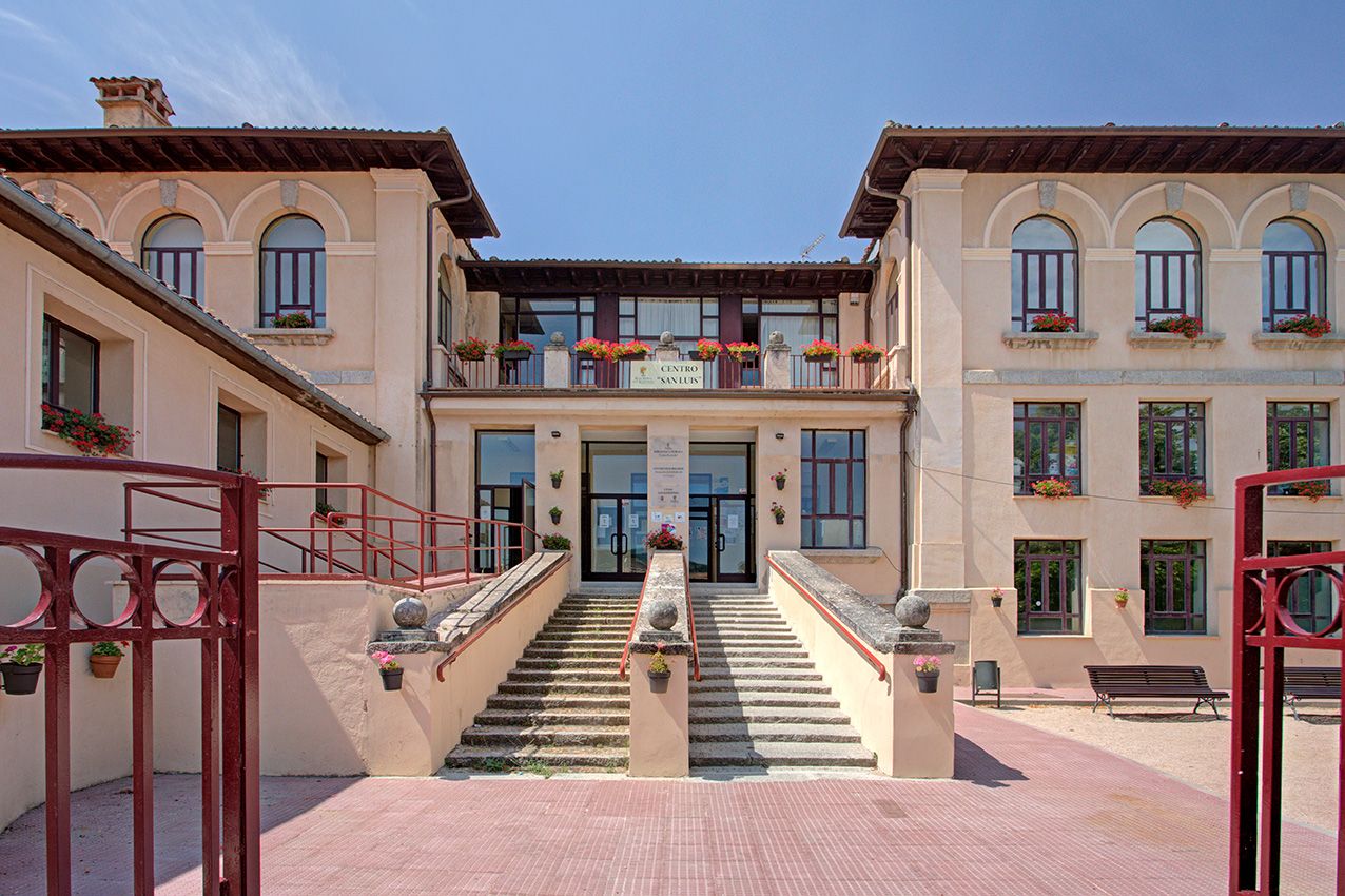 Elegant Italian-style villa with grand staircase, arched windows, and red iron railings under a clear blue sky.