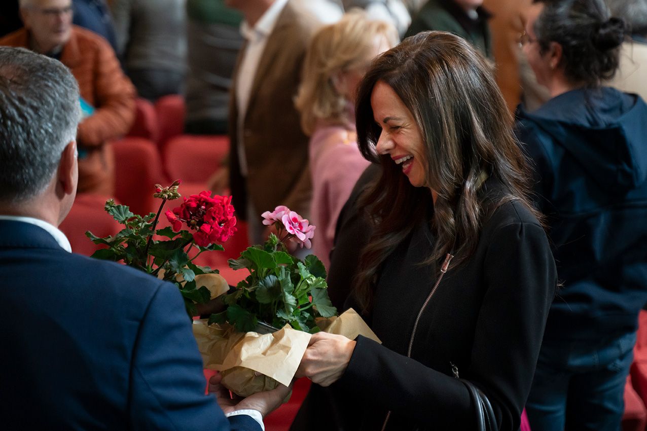 Smiling woman receives bouquet of roses at a garden conference networking event.