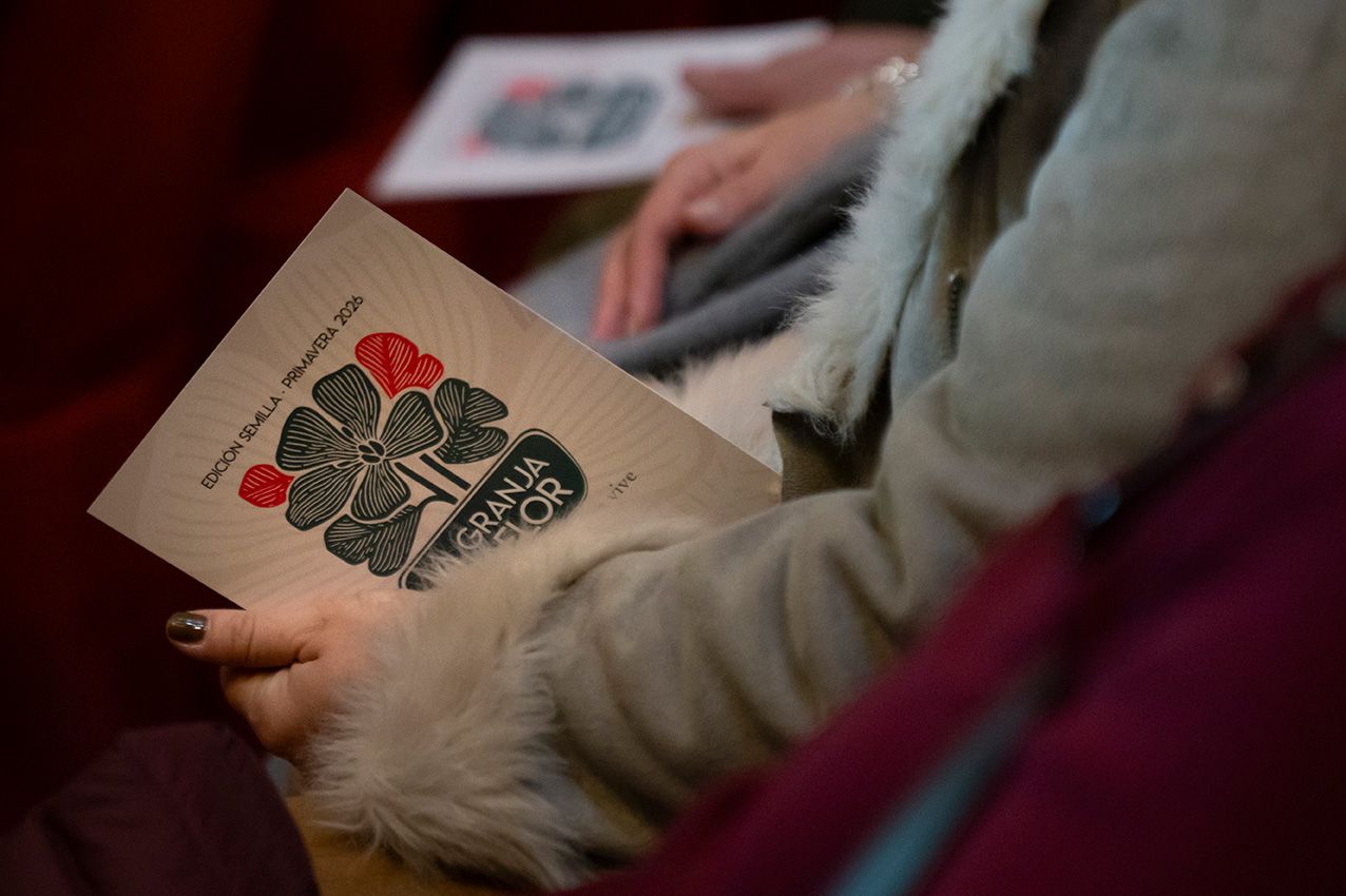Attendee holds illustrated program booklet with floral design at a garden art conference.