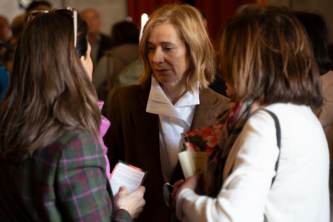 Three women engaged in conversation at an indoor social gathering event.