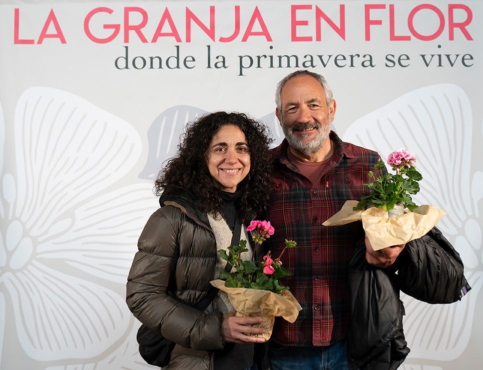 Couple smiling and holding potted pink flowers at La Granja en Flor spring festival event.