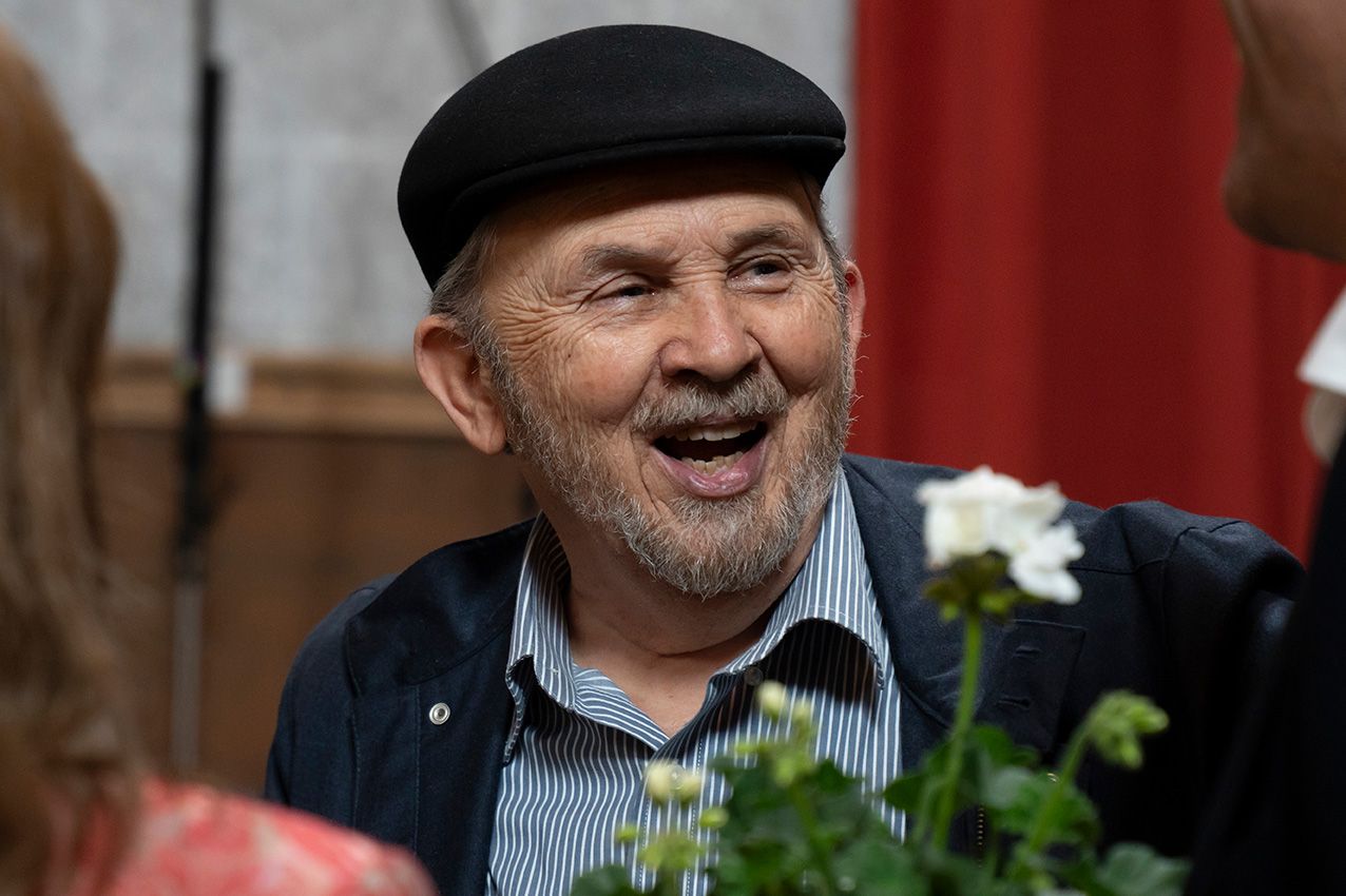 Happy elderly man wearing black beret laughing at outdoor floral spring festival.