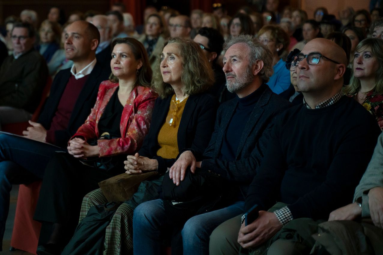 Group of five adults seated in an audience at an indoor cultural event.