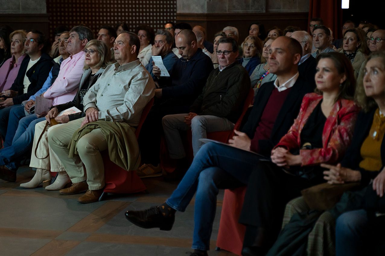 Large audience seated attentively in rows at an indoor conference or cultural presentation event.
