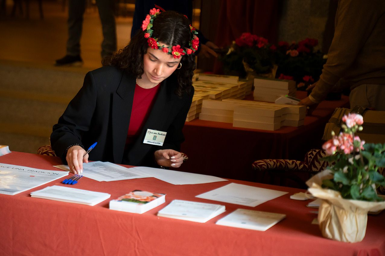Young woman with floral crown writing at a registration table at a spring event.