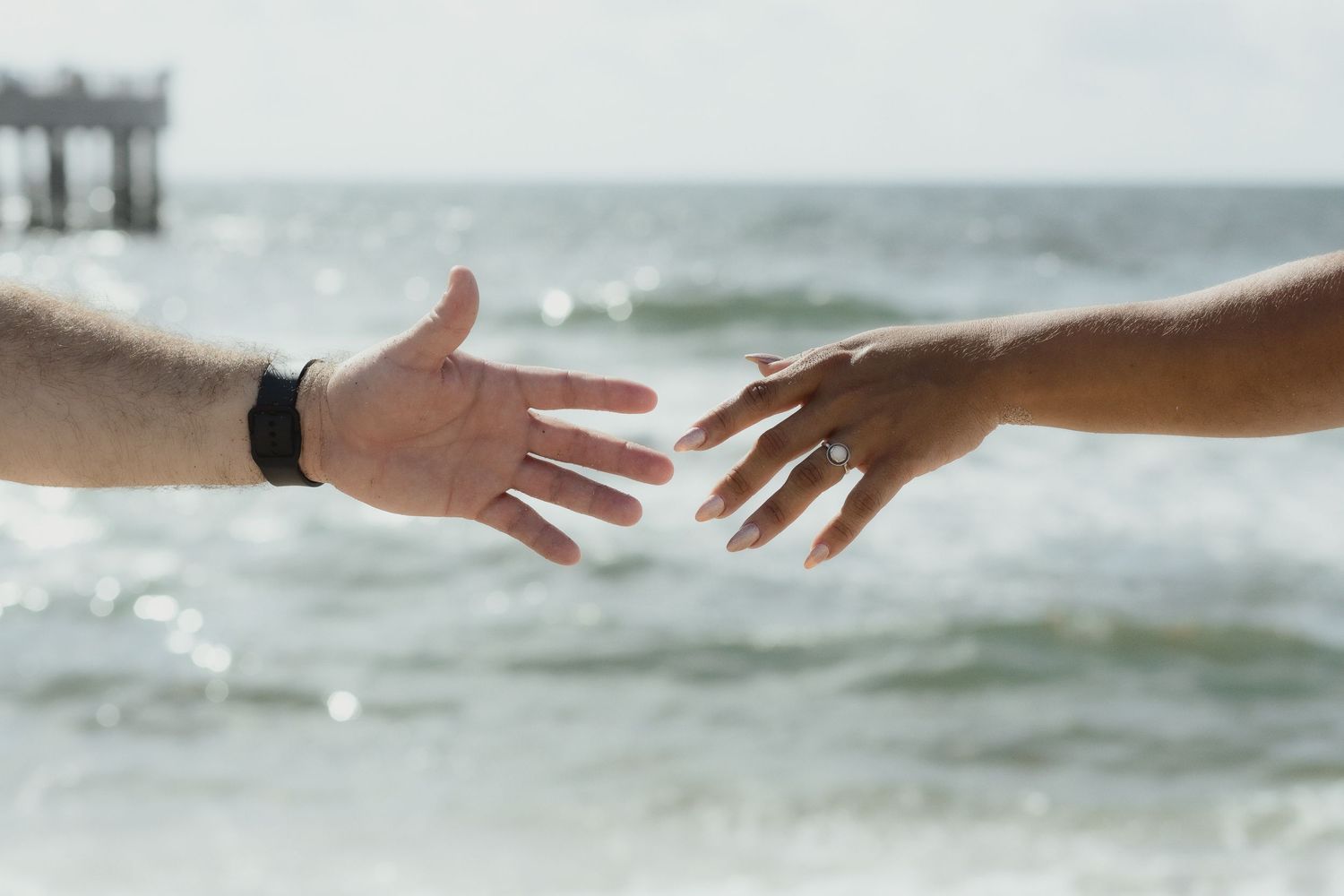 Couple holding hands at Pompano Beach Pier during engagement couples session.