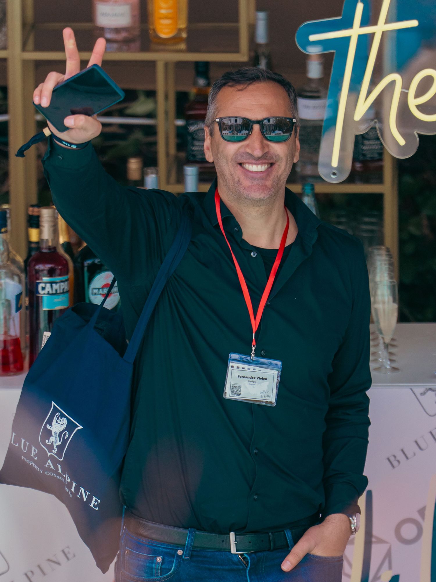 A group wearing dark clothing and lanyards smiles at a professional event or conference.