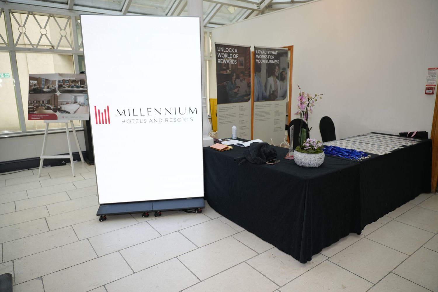 Millennium bank display booth with branded banner sign and black draped table at a corporate event.