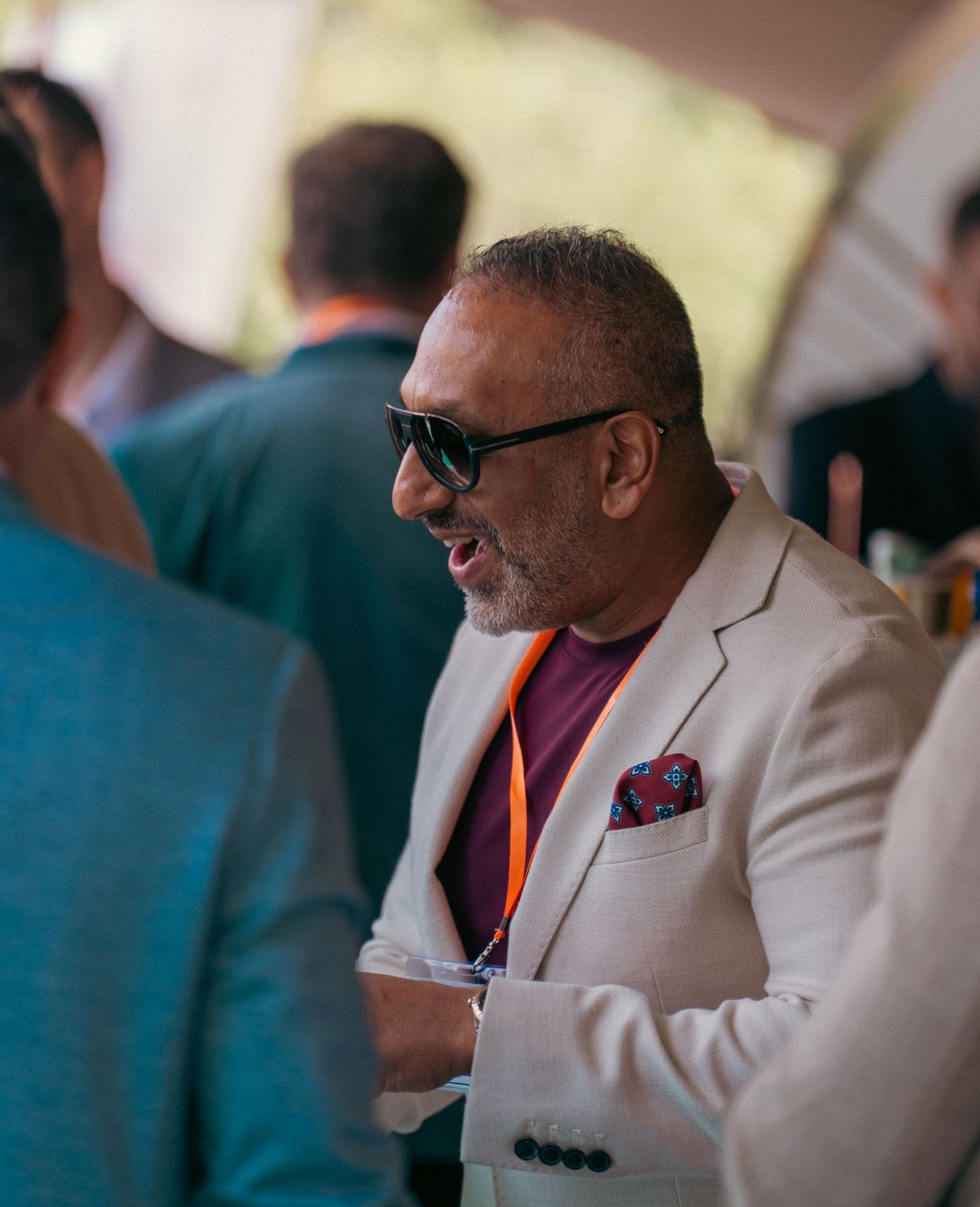 A person in a light colored blazer and pocket square sits at a formal event.