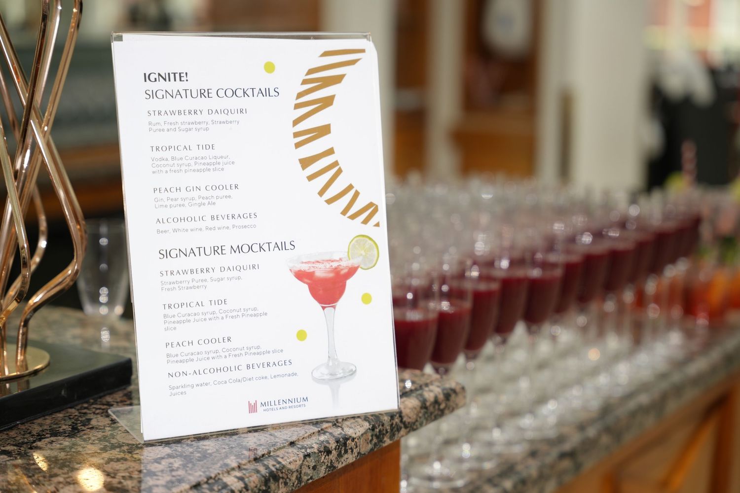 Ignite signature cocktails menu displayed at a bar with pink martinis and red shot glasses at an event.