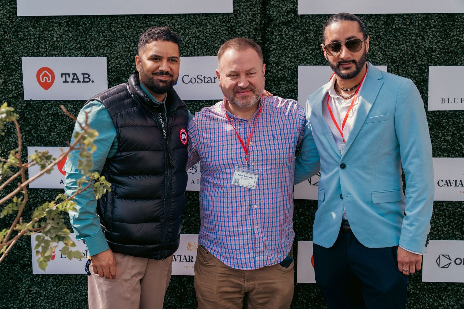 Corporate event attendees posing in front of branded step-and-repeat wall.