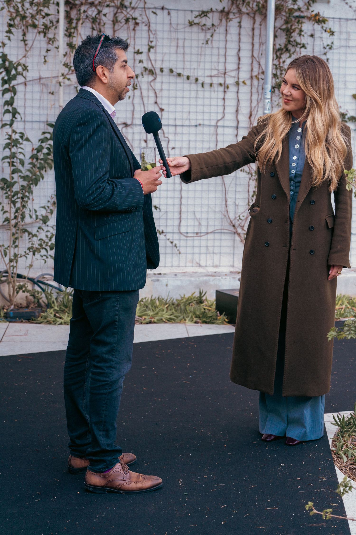 Two people interact with microphones during an outdoor presentation or interview.