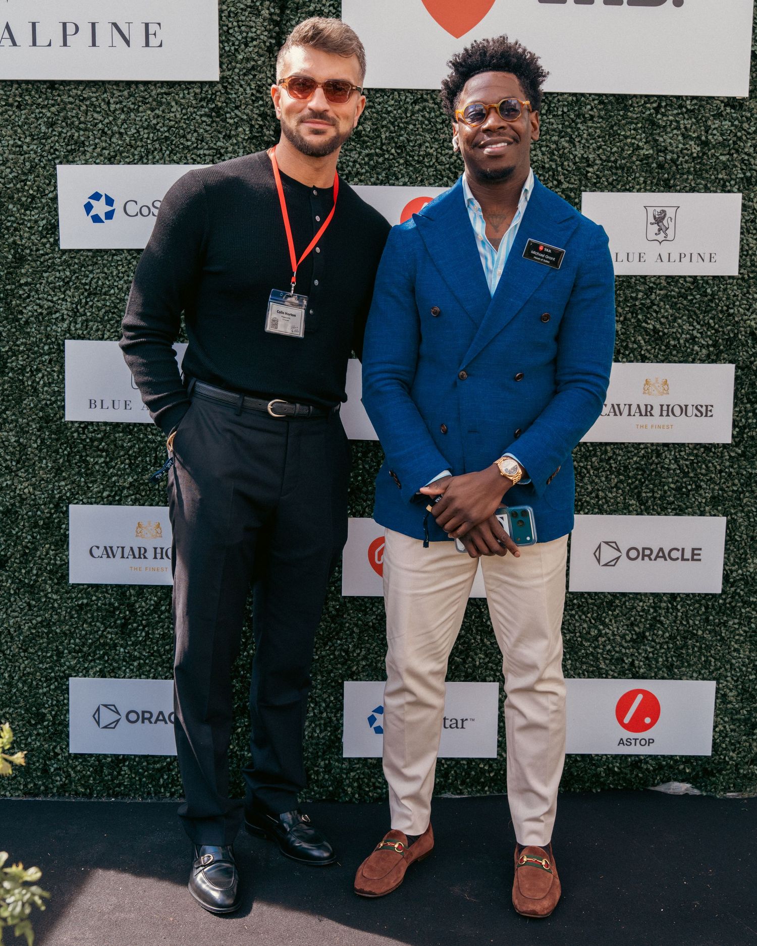 Business professionals networking in front of sponsor wall at corporate event.