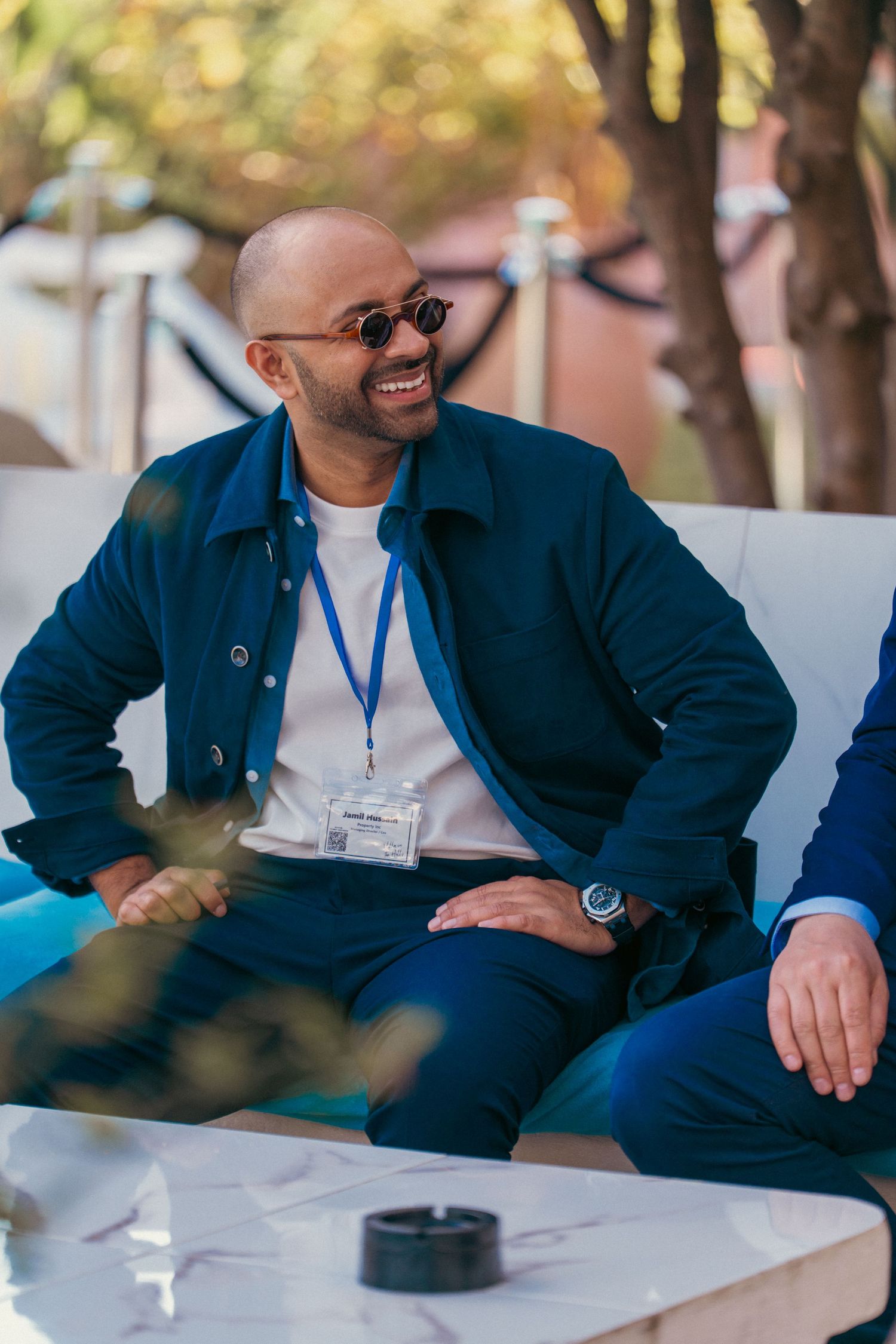 People in casual business attire seated and socializing at outdoor event.