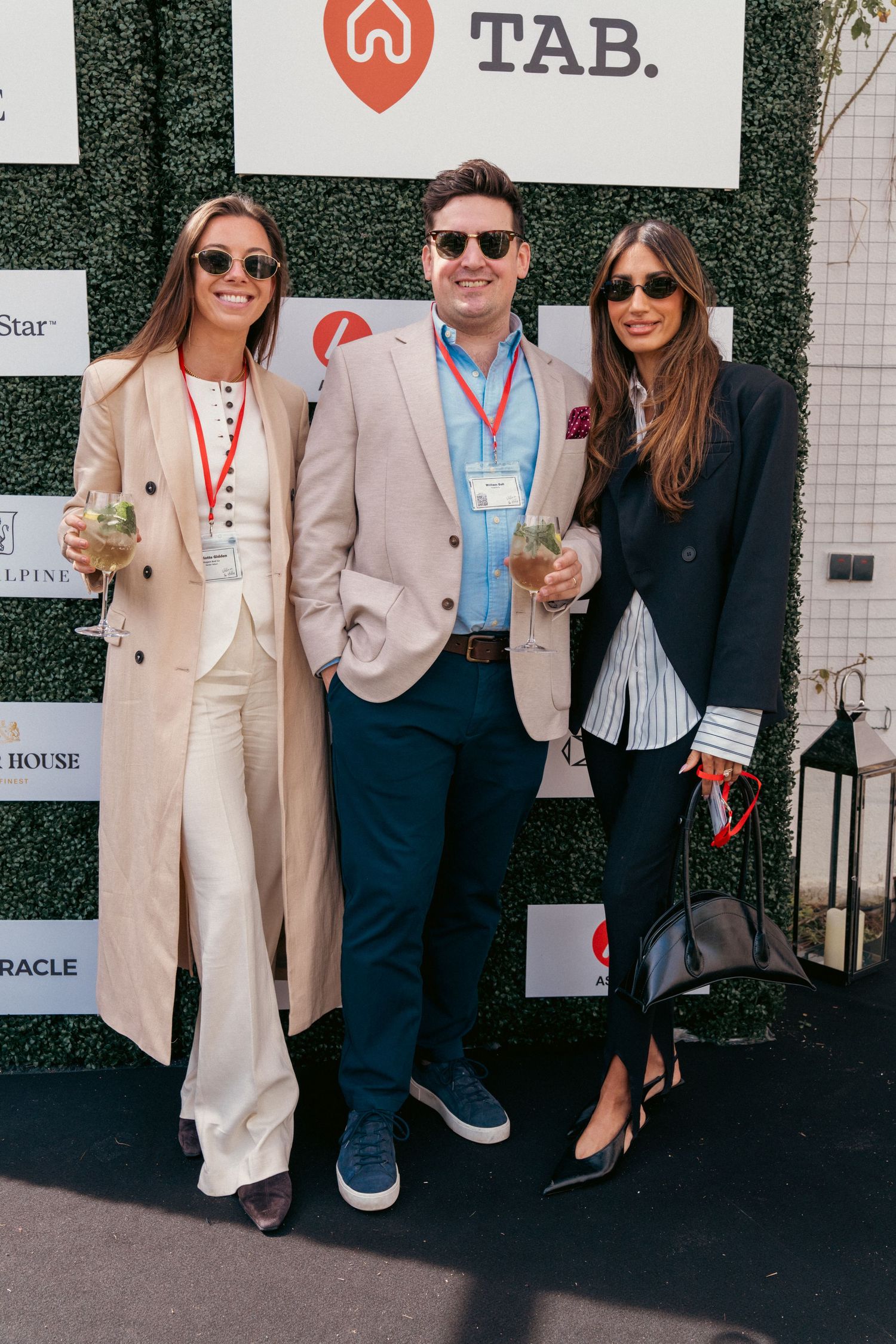 Event attendees socializing in front of step-and-repeat banner with company logos.